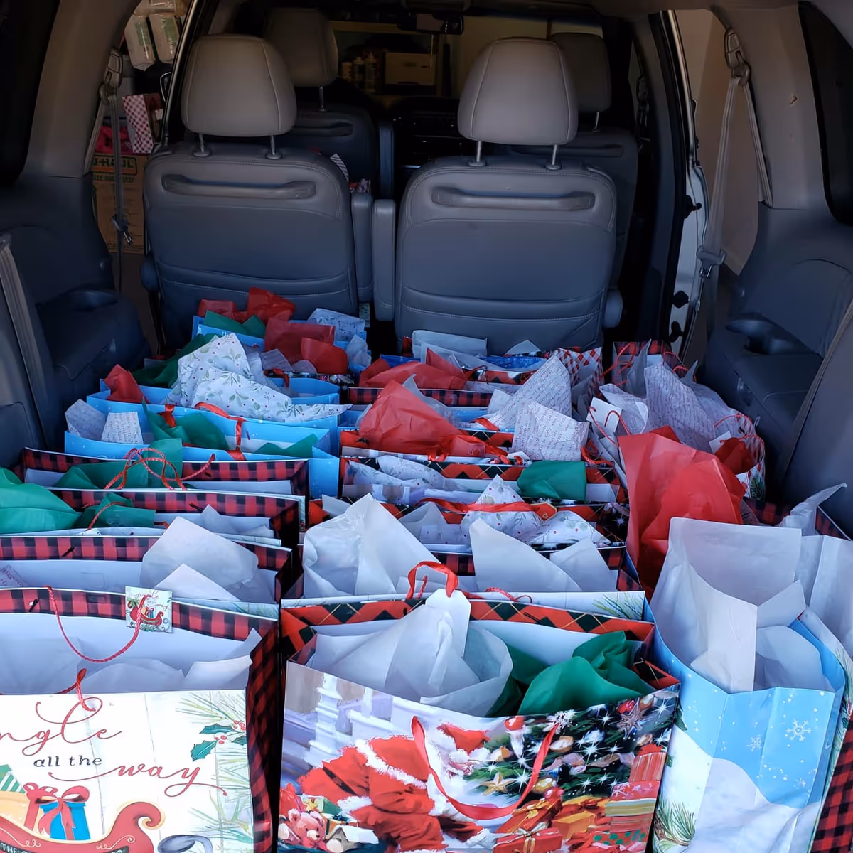 Back of an SUV filled with many colorful gift bags.
