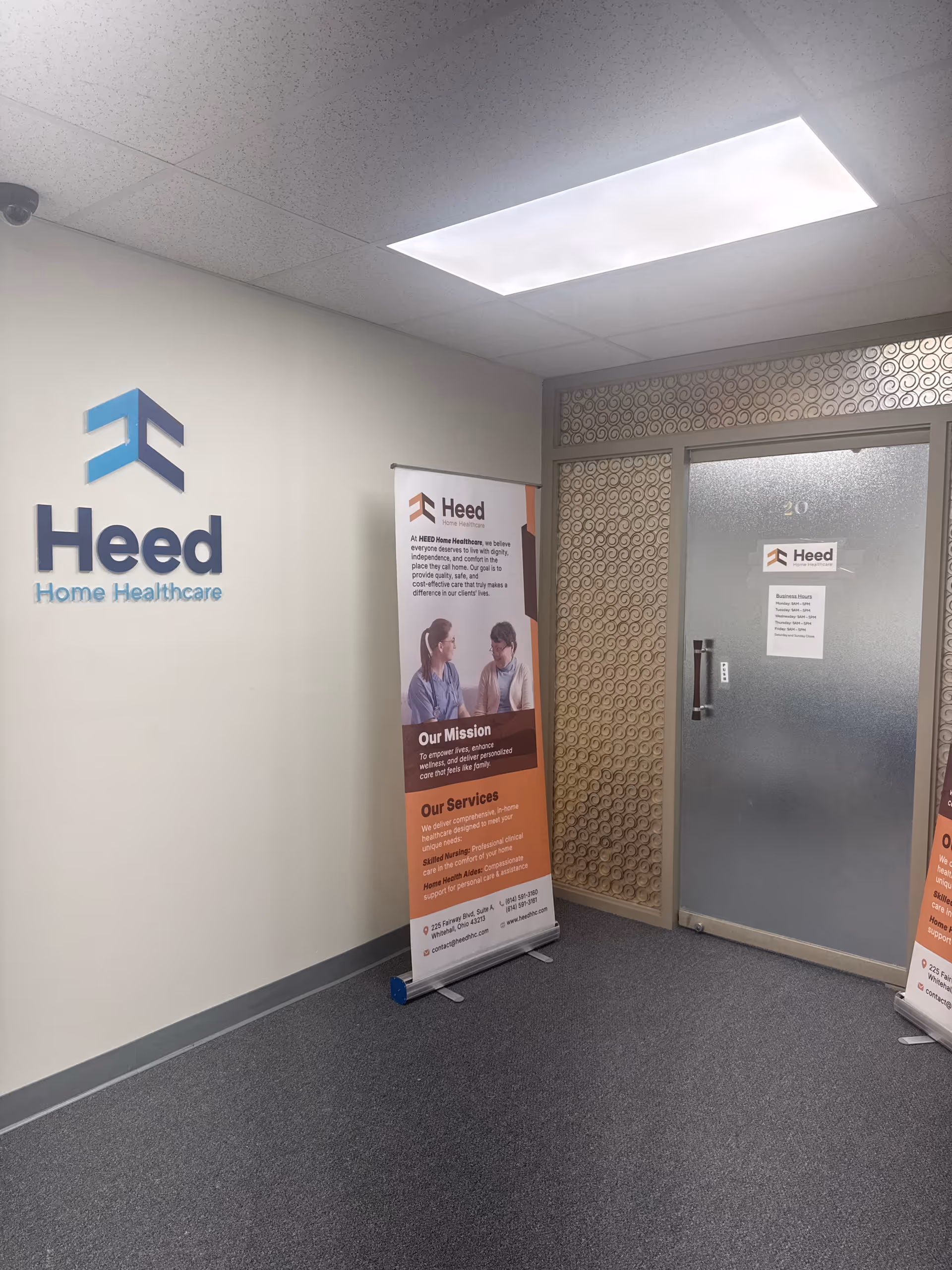 Interior hallway with Heed Home Healthcare logo and banners beside a frosted door.