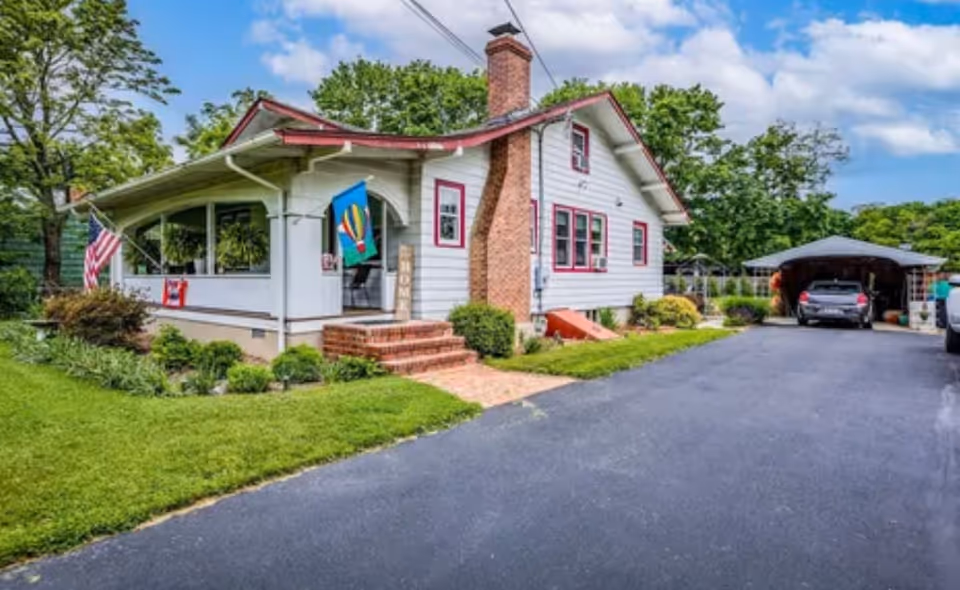 A white, single-story senior care home with a brick chimney and driveway.