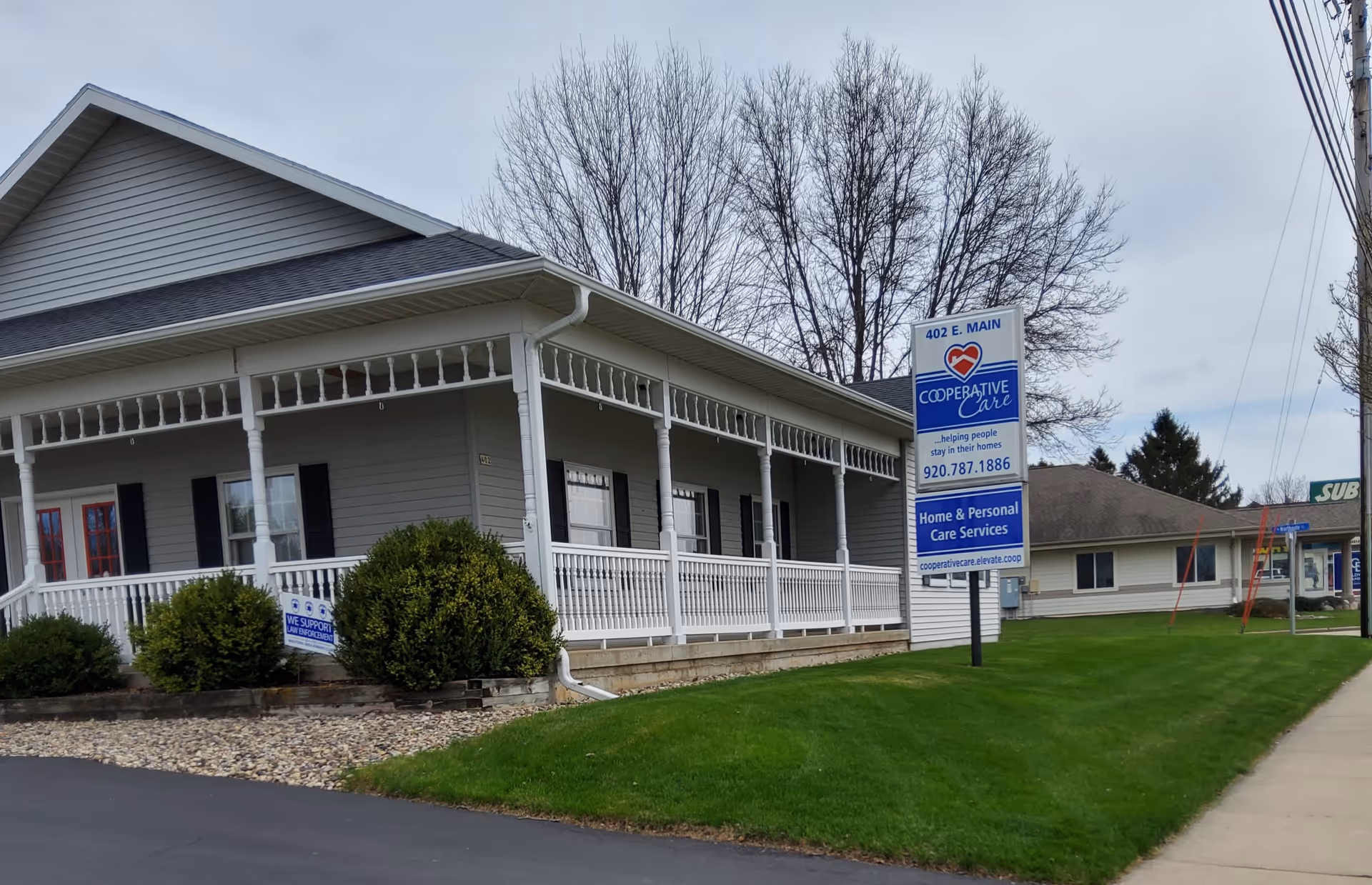 Single-story facility with wraparound porch, manicured lawn, and Cooperative Care sign.