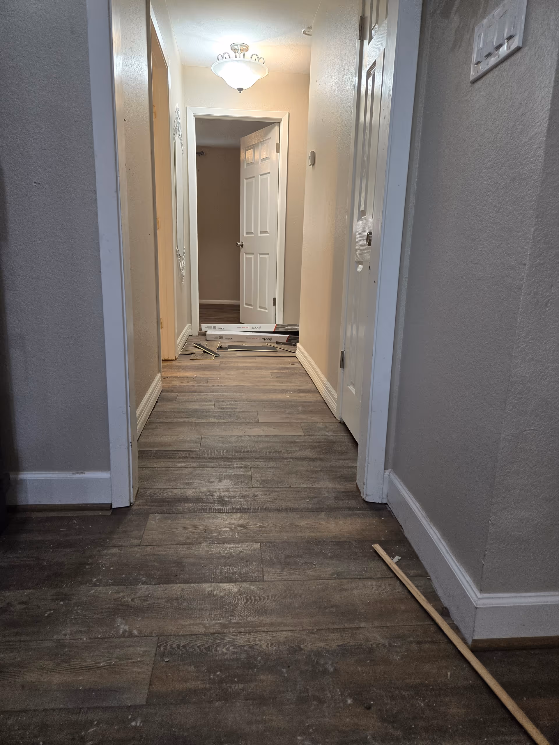 Indoor hallway in a facility with doors, debris, and a ceiling light