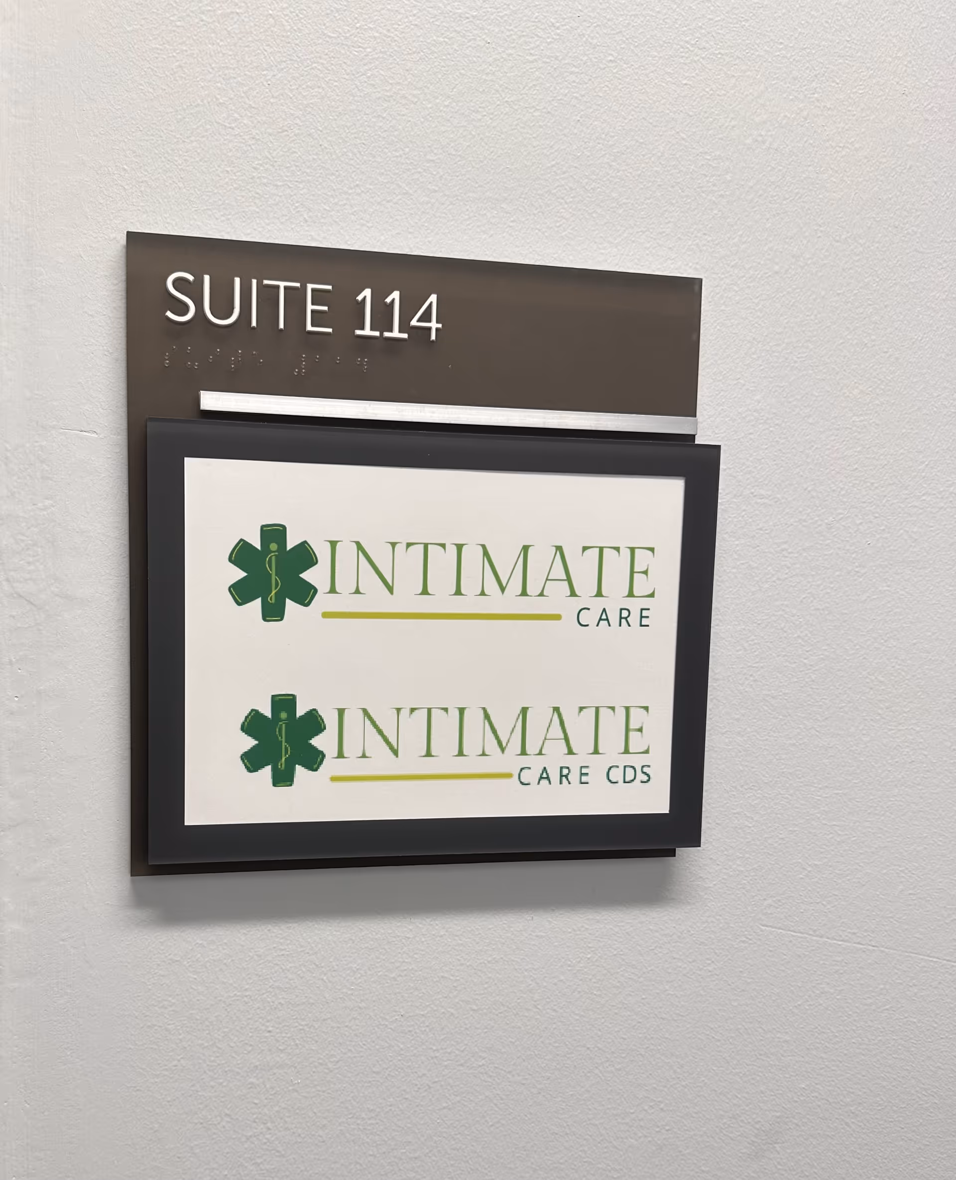 Interior wall with Suite 114 sign and two Intimate Care logos on a lit plaque.