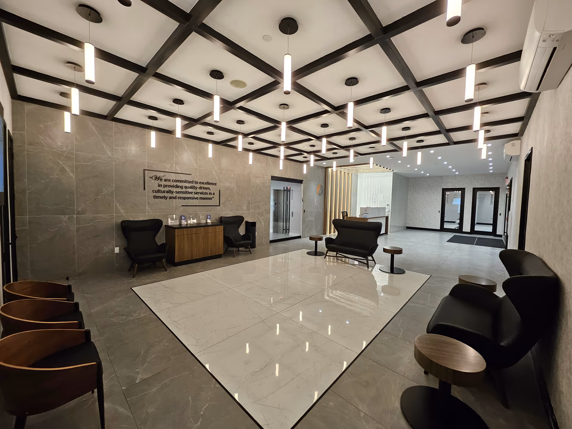 Modern lobby with marble floors, pendant lights, and arranged seating for visitors.