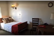 A small bedroom with a bed, chair, and round table in a senior living facility.