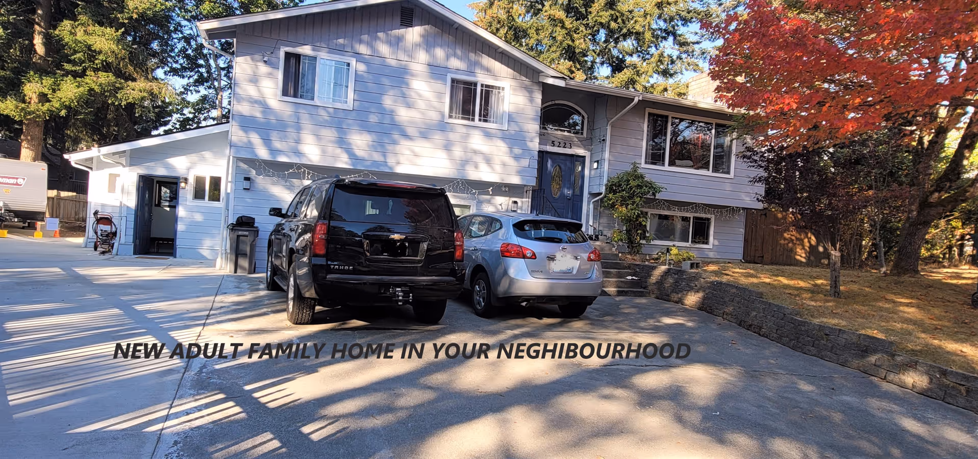 Two-story light-blue adult family home with parked cars in the driveway.