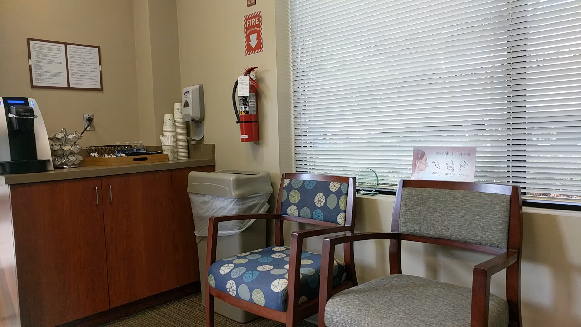 Two chairs beside a coffee station in a bright indoor lounge area.