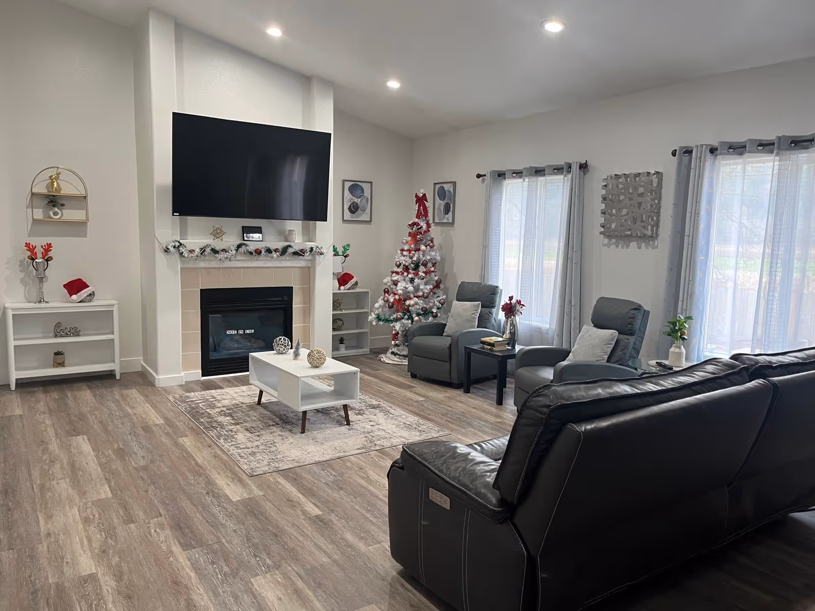Bright, modern living room with fireplace, TV, Christmas tree, and leather seating.