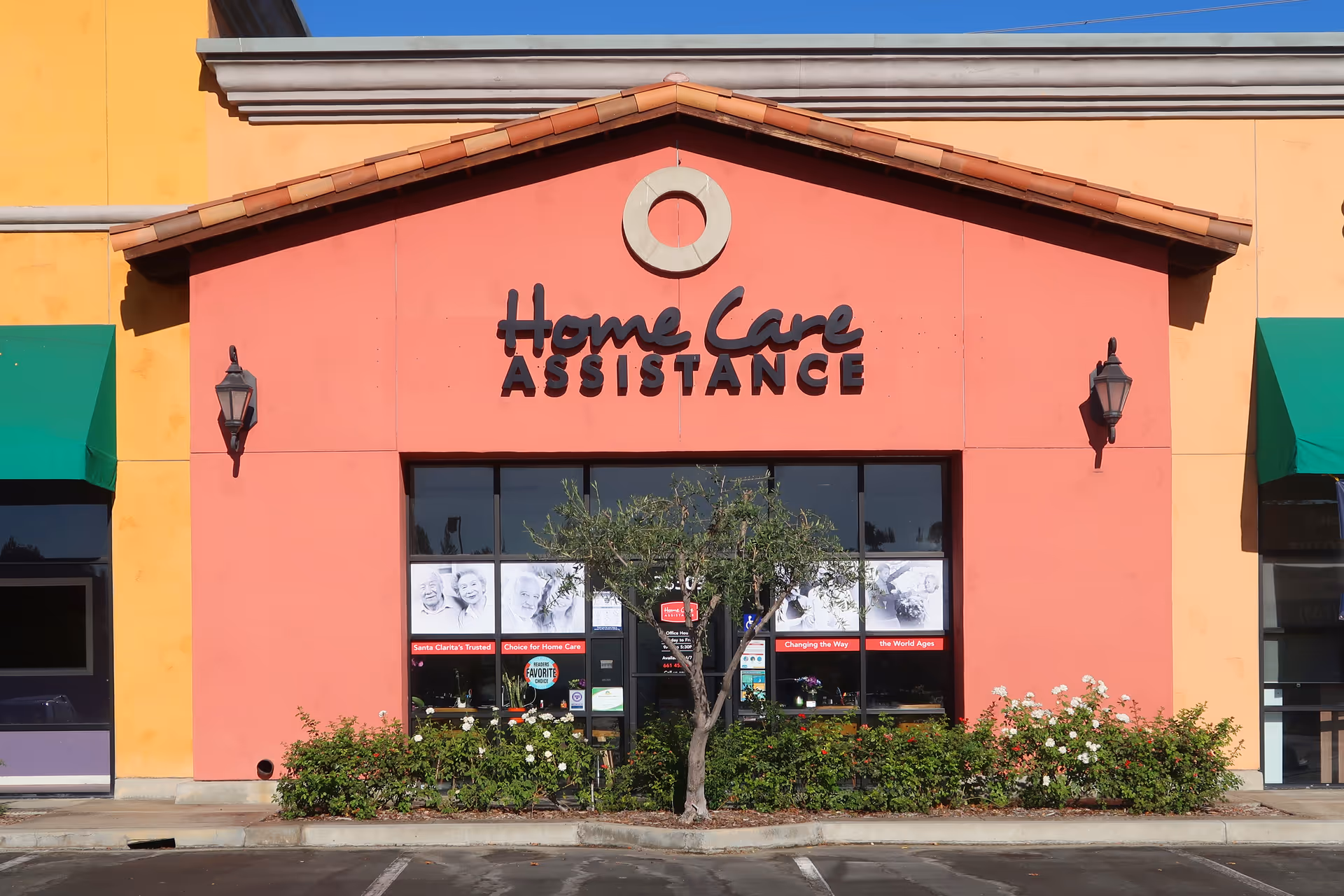 Colorful building facade with Home Care Assistance storefront and a tree in front.