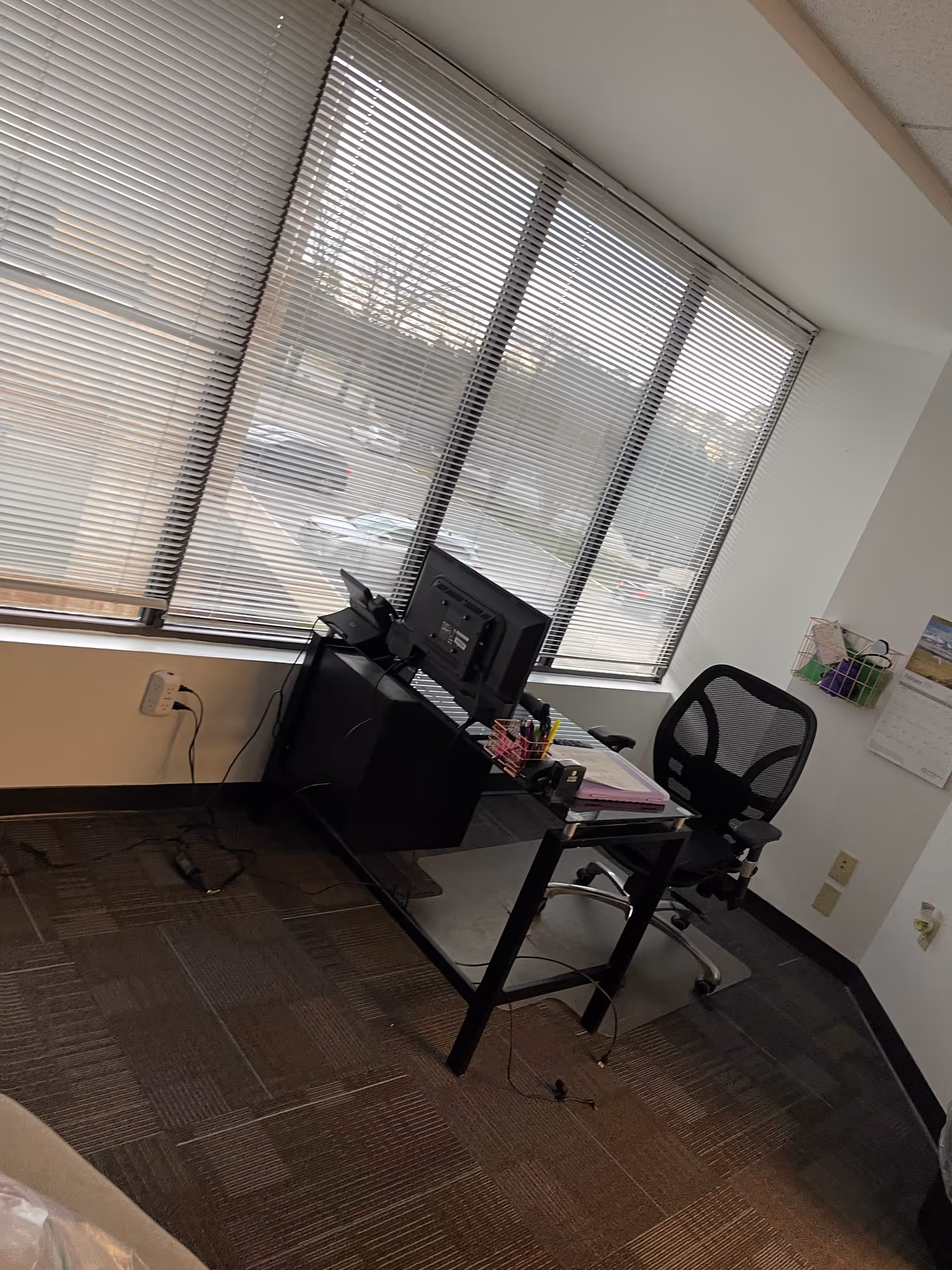 Office desk with computer, chair, and large window blinds.