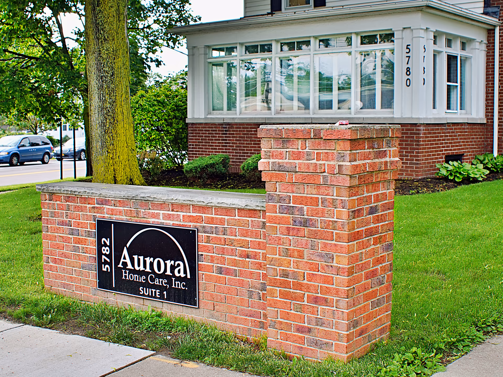 Brick sign wall with Aurora Home Care, Inc. plaque in front of a brick building.