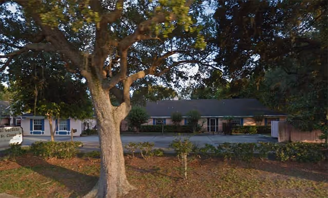 Front exterior of Royal Gardens of St Cloud, with trees and a parking area.