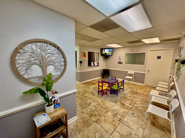 Facility lobby with a colorful children's table and chairs near a reception window.