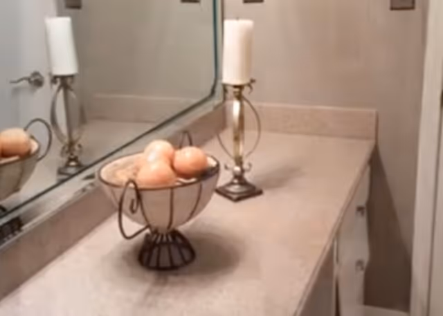 Bathroom vanity with fruit bowl, two candle holders, and a large mirror above the counter