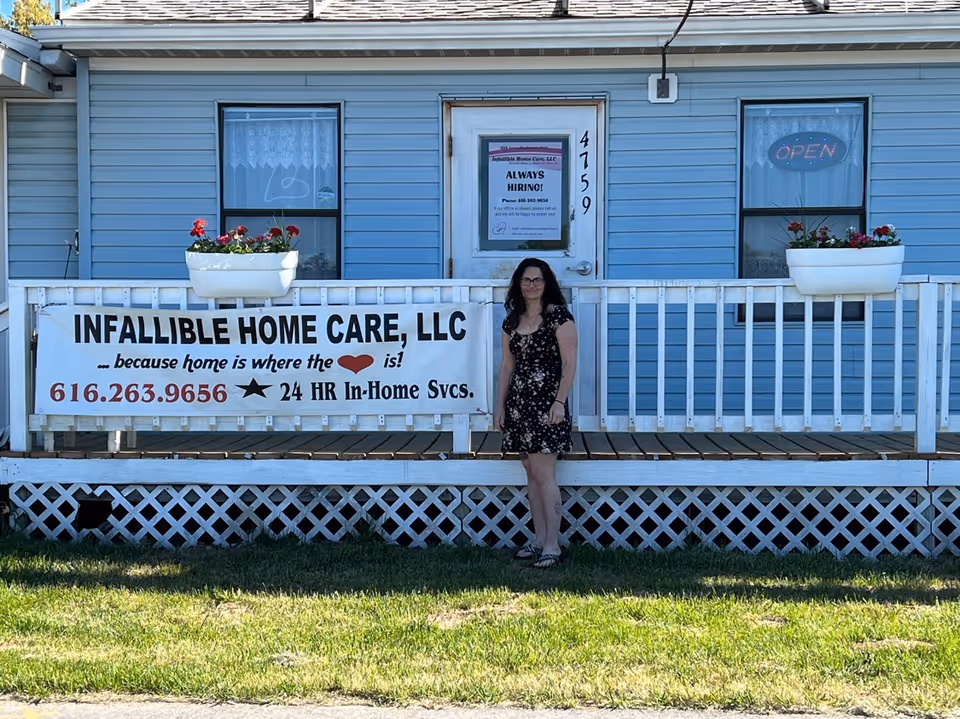 A blue exterior building with a banner reading INFALLIBLE HOME CARE, LLC and a woman standing.