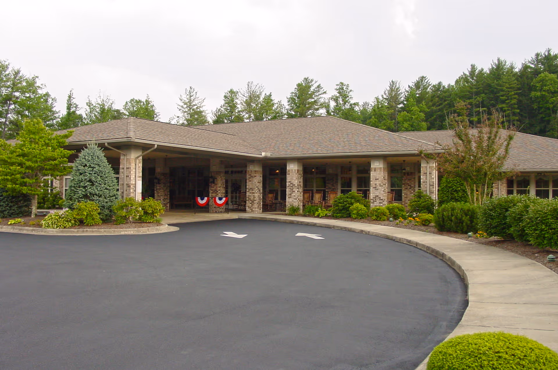 Front view of Brookdale Lenoir entrance with curved driveway and landscaped greenery.