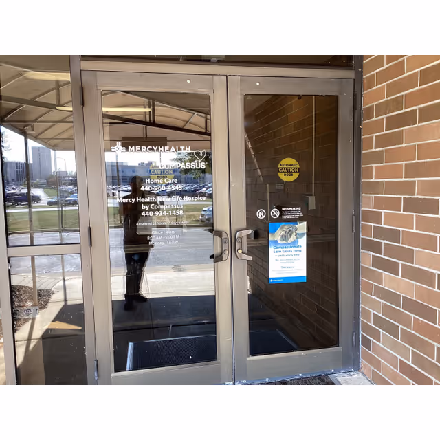 Glass double doors with Mercy Health Home Care by Compassus signage at a brick building entrance.