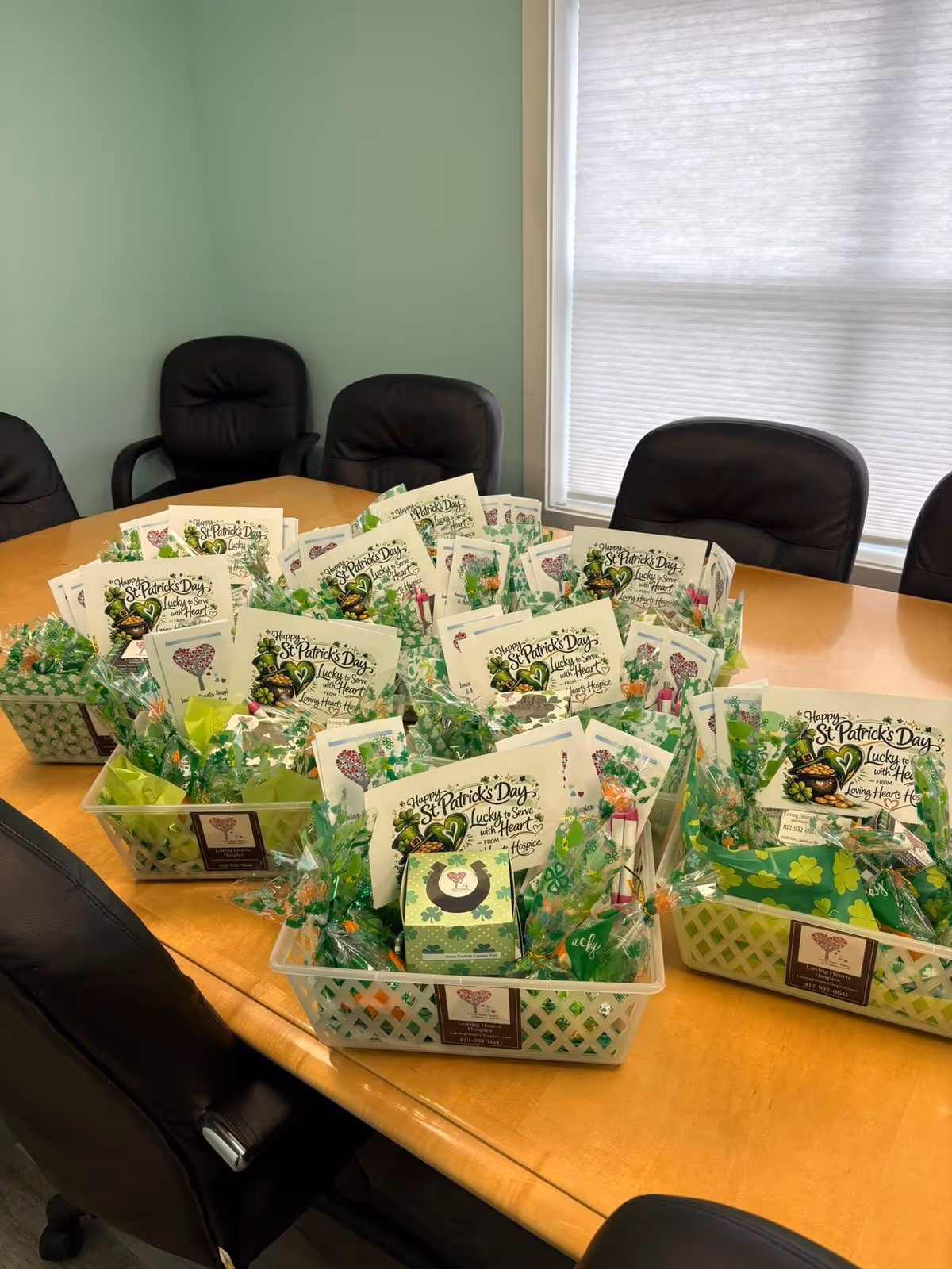 Conference table piled with St Patrick's Day cards and gift baskets in a bright room.