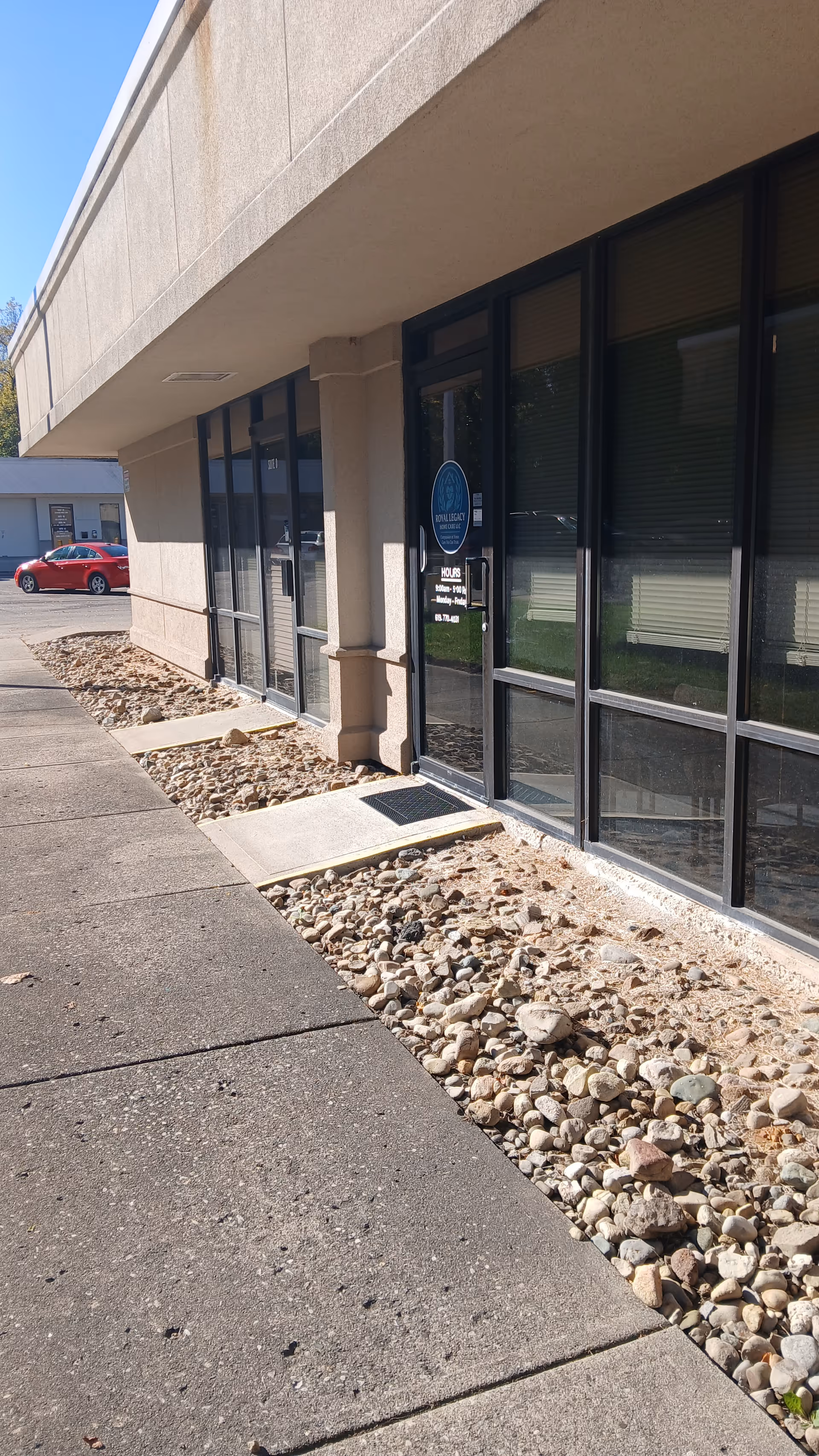 Exterior view of Royal Legacy Home Care entrance with glass doors and rocky landscaping.
