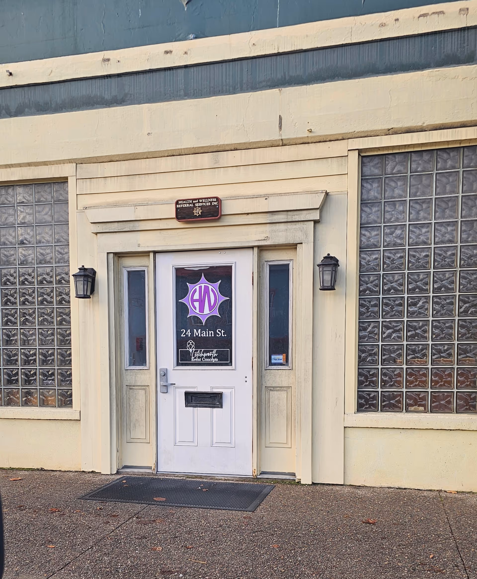 Exterior view of a facility entrance with glass block windows and purple logo on the door.