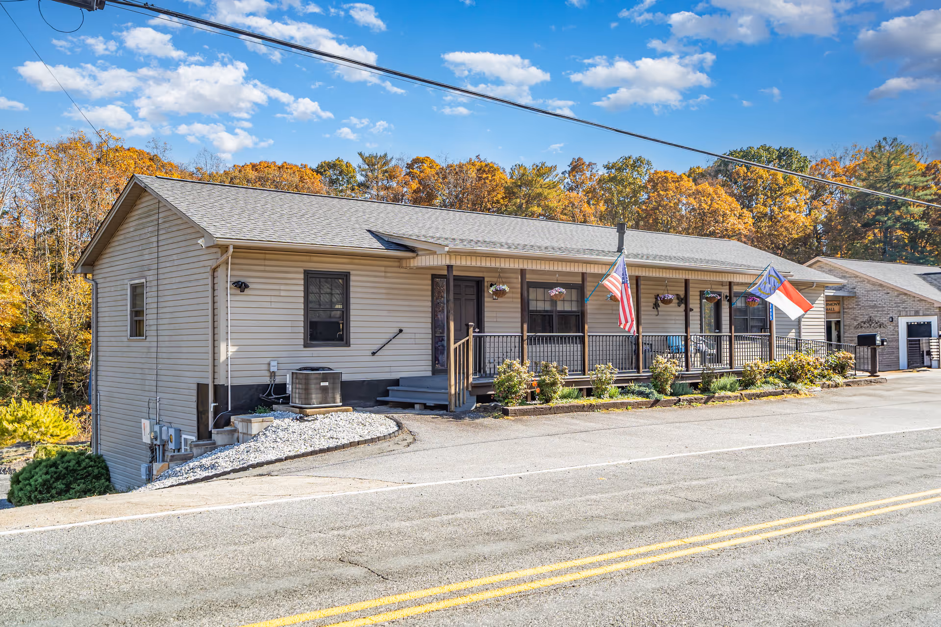 Single-story beige facility with a wraparound front porch and two flags.