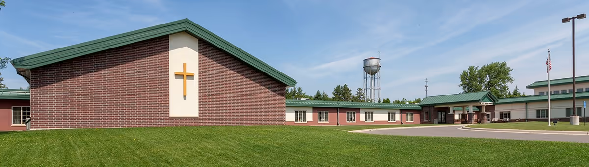 Exterior view of Guardian Angels Health & Rehab Center: brick building with green roof and lawn.