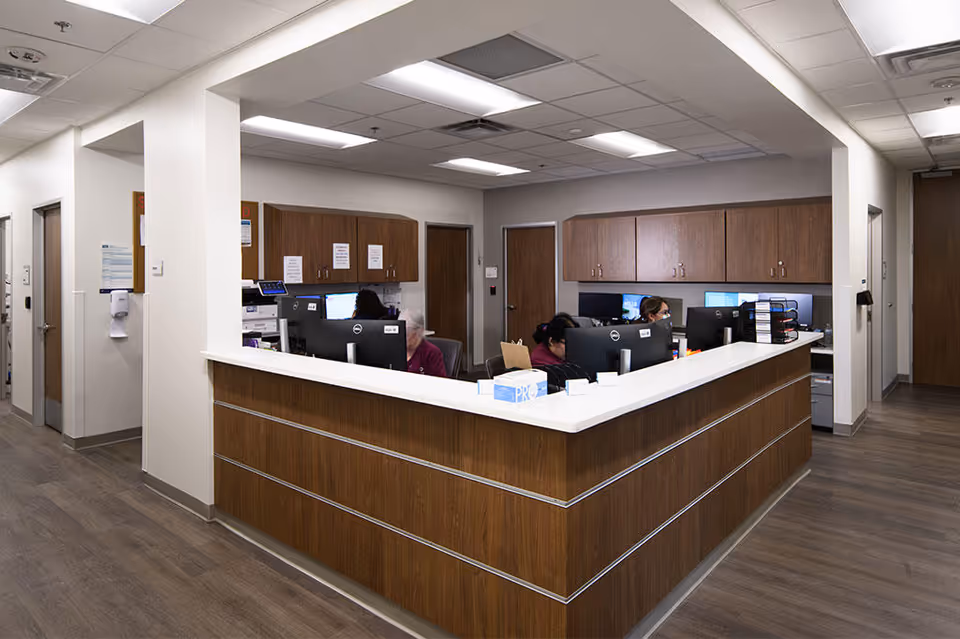 A U-shaped reception desk with staff computers in a medical facility lobby.