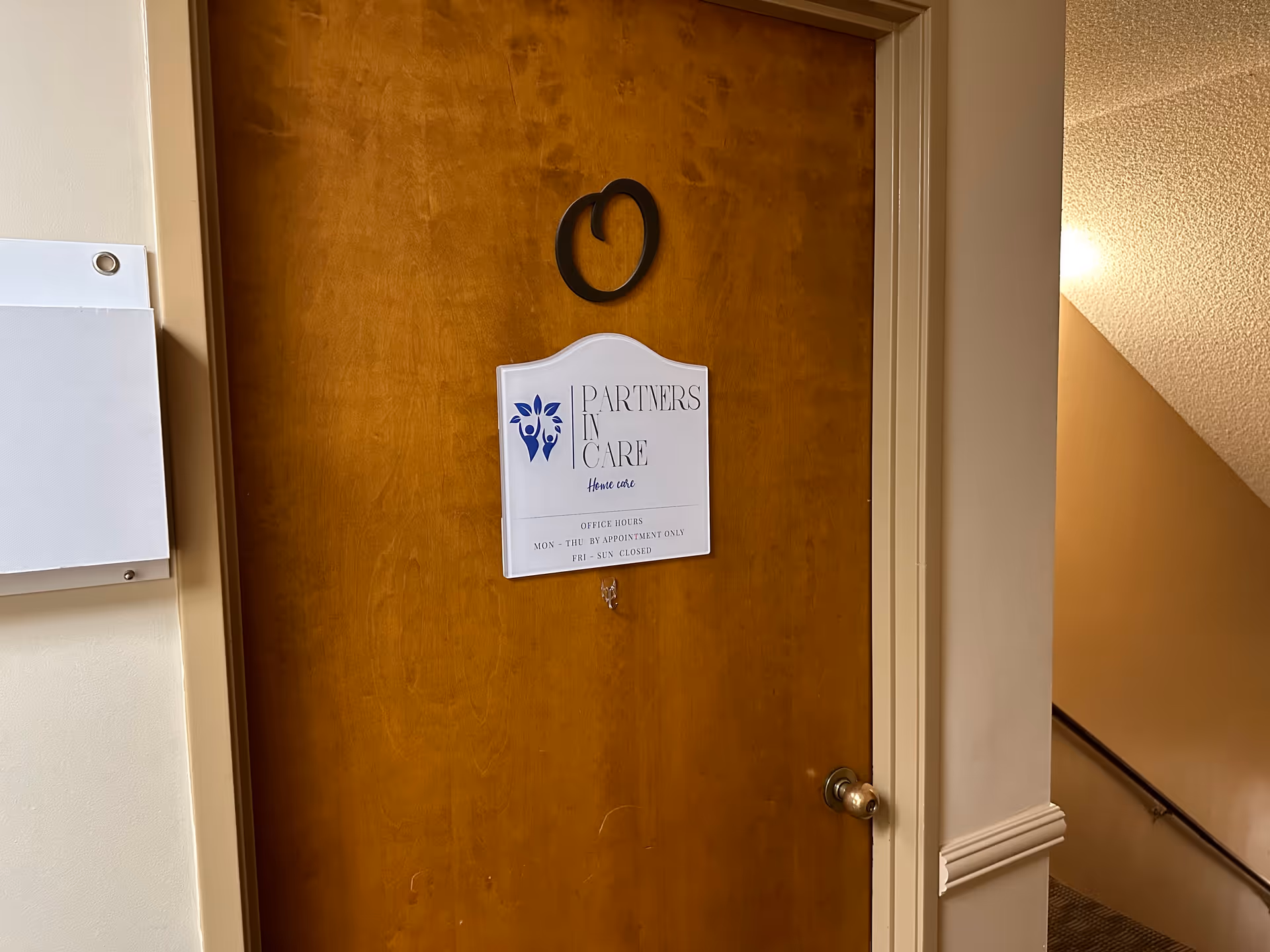 Wooden door with Partners In Care Home Care sign in a hallway interior.