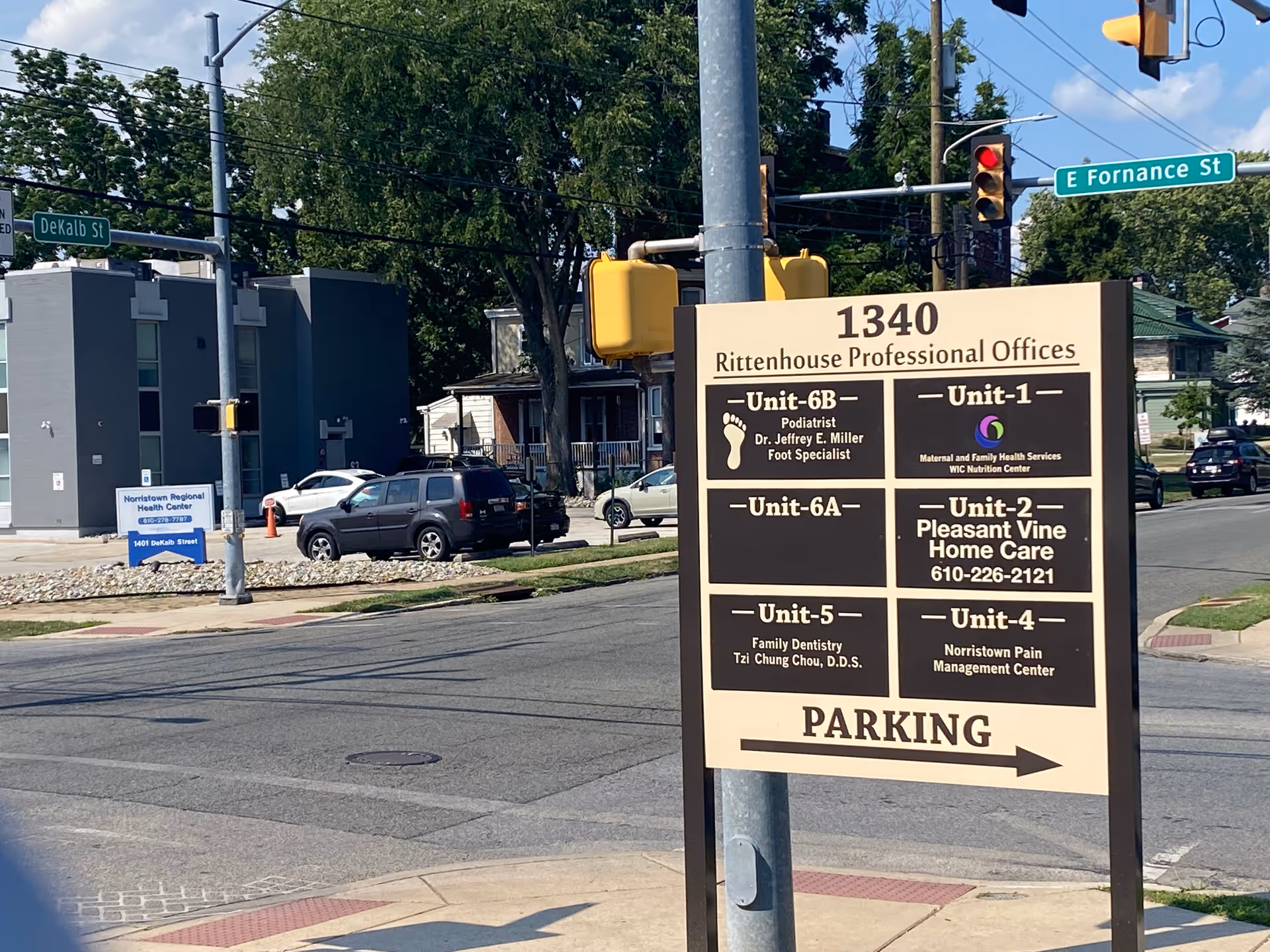 Street intersection featuring a large Pleasant Vine Home Care sign and building directory.