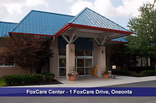 Front entrance of a care facility with glass doors and a blue metal roof.