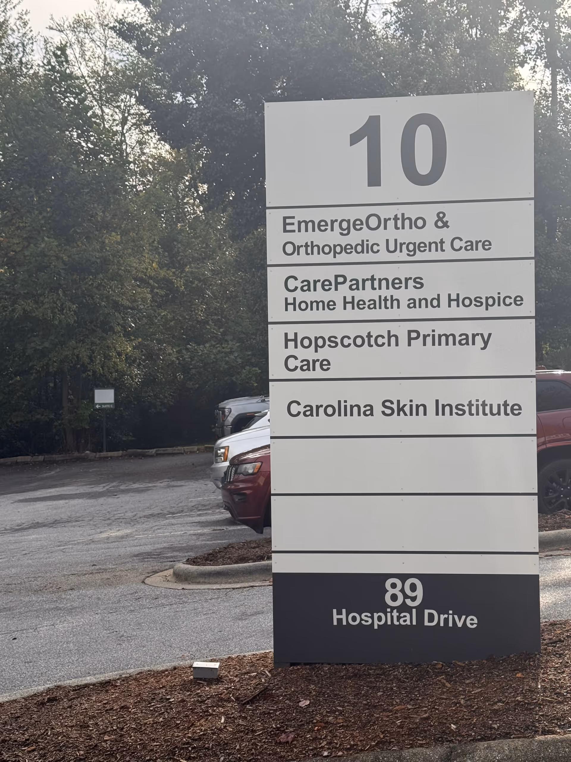 Large outdoor sign displays multiple tenants, including CarePartners Home Health and Hospice, in a parking lot.