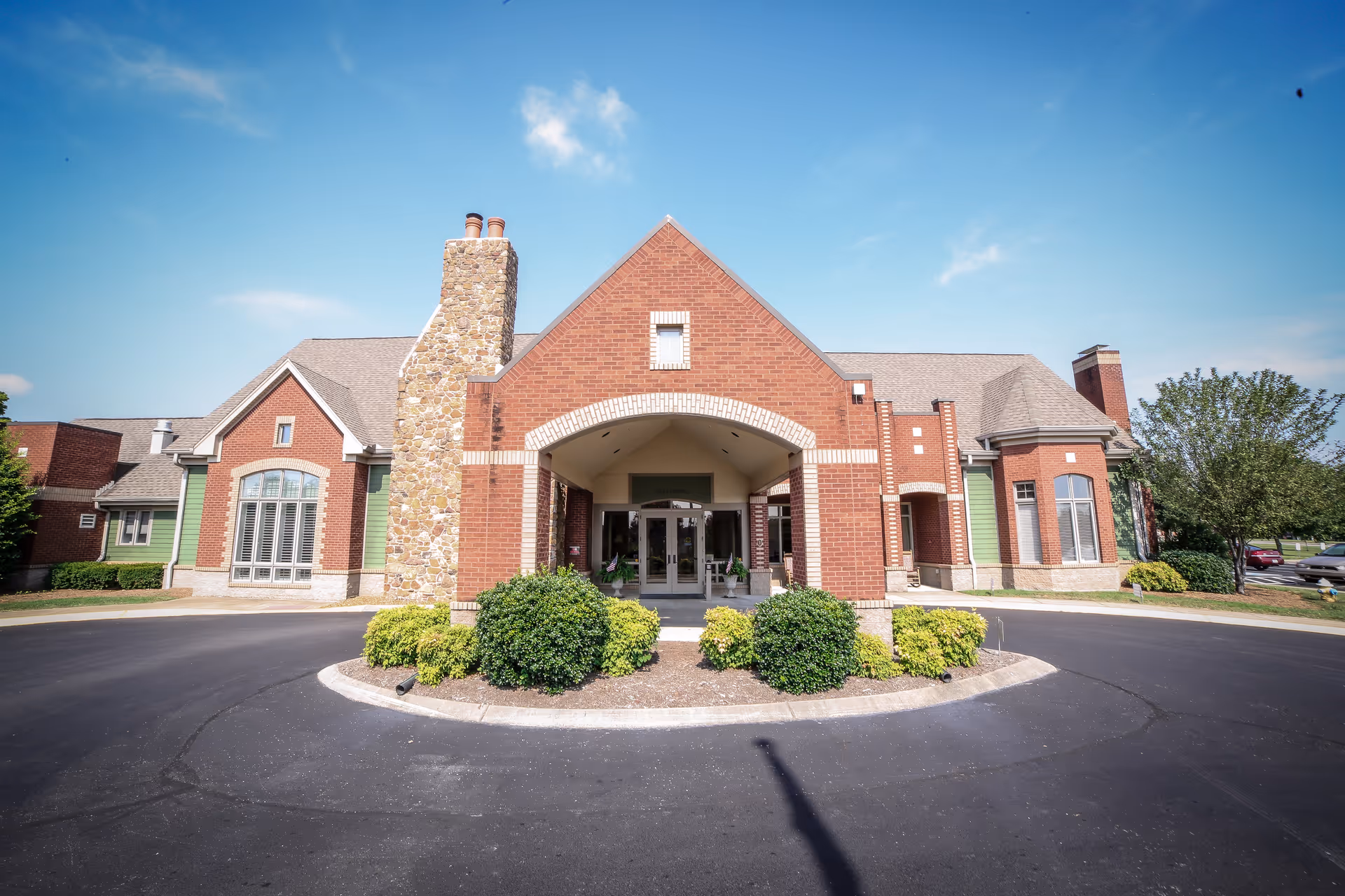 A brick building with a stone accent and landscaped entrance at Hearthside Senior Living.