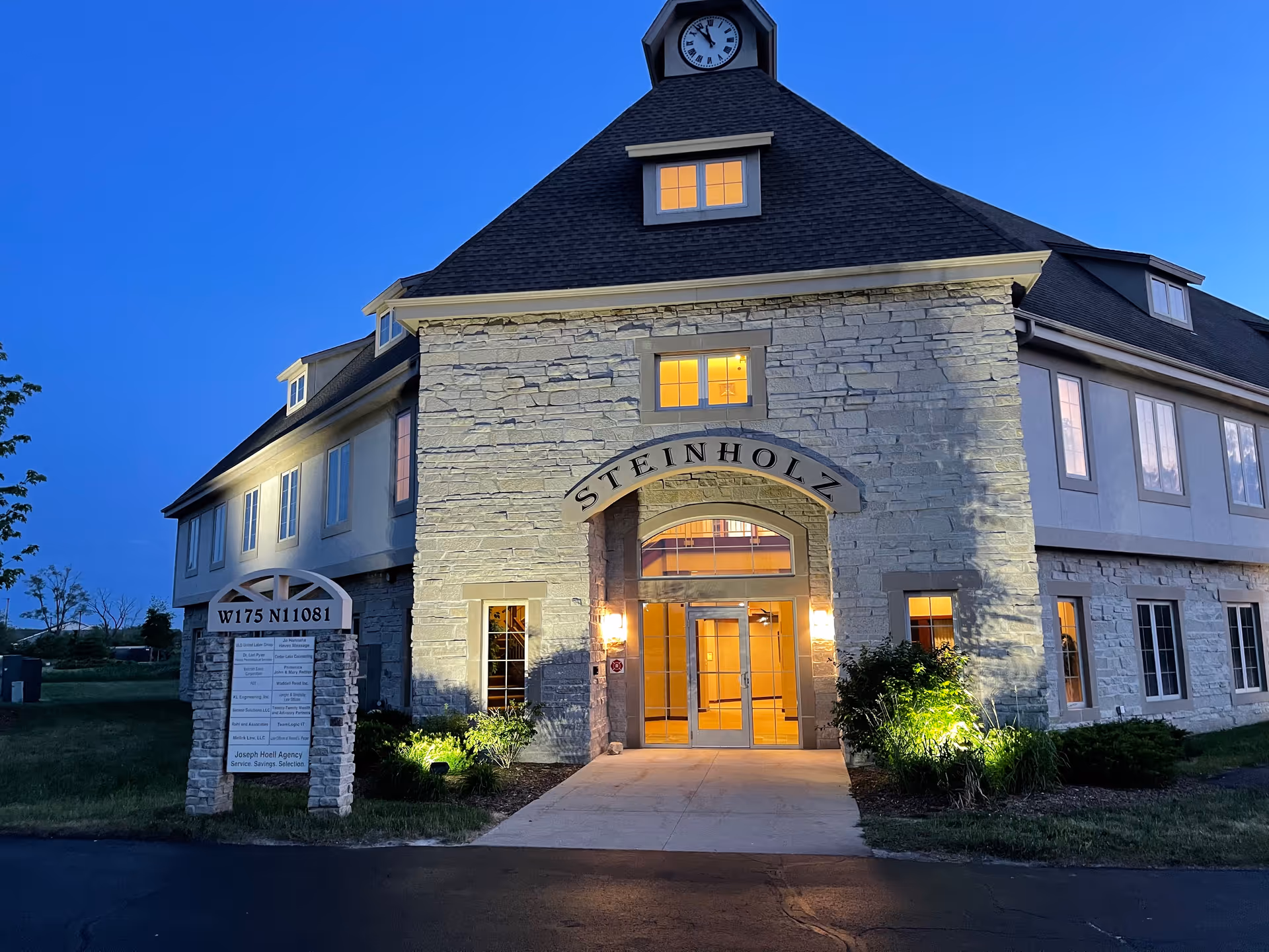 Exterior view of a stone senior living facility entrance at dusk.