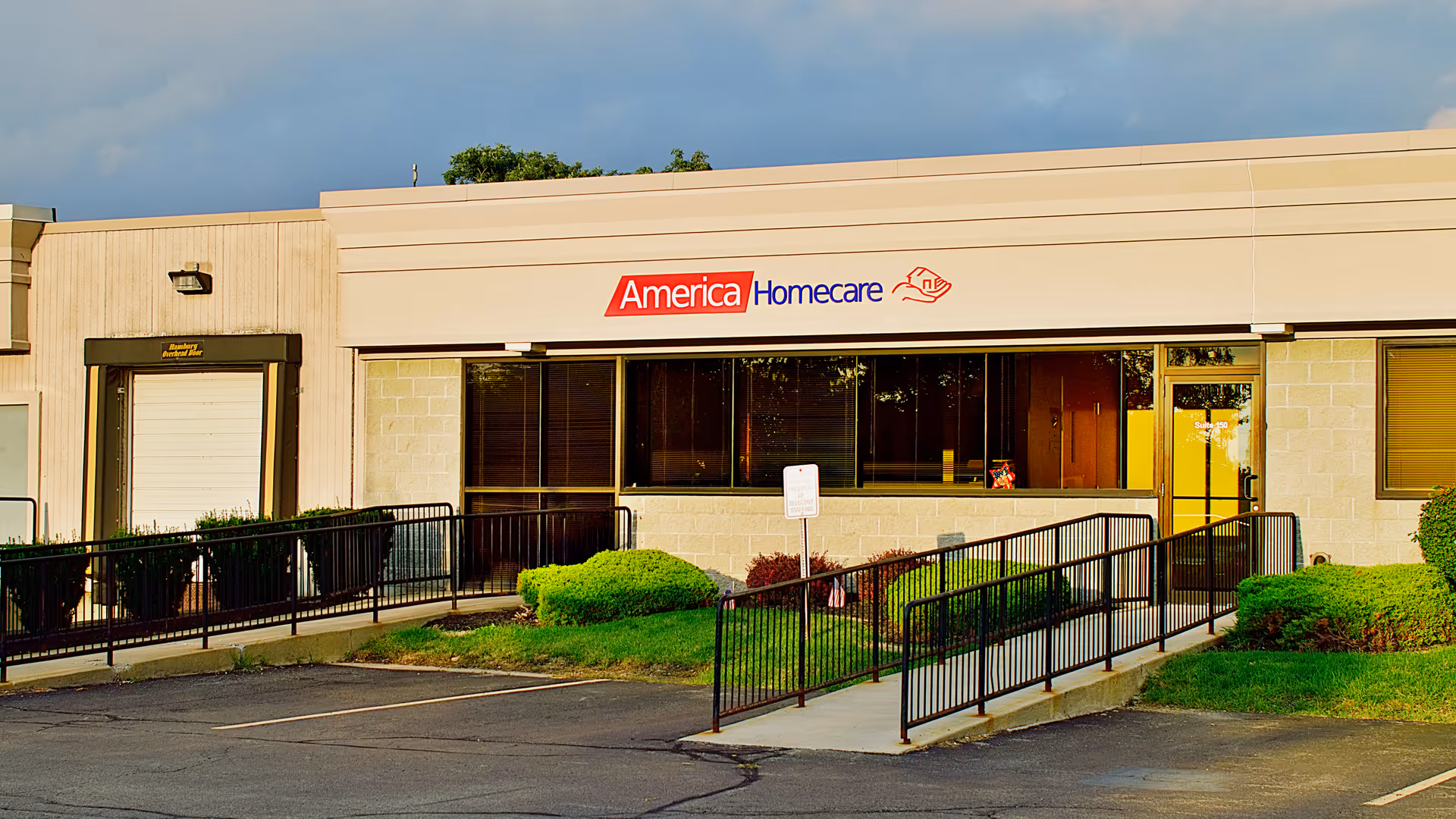 Exterior view of a single-story facility with America Homecare sign and ramp.