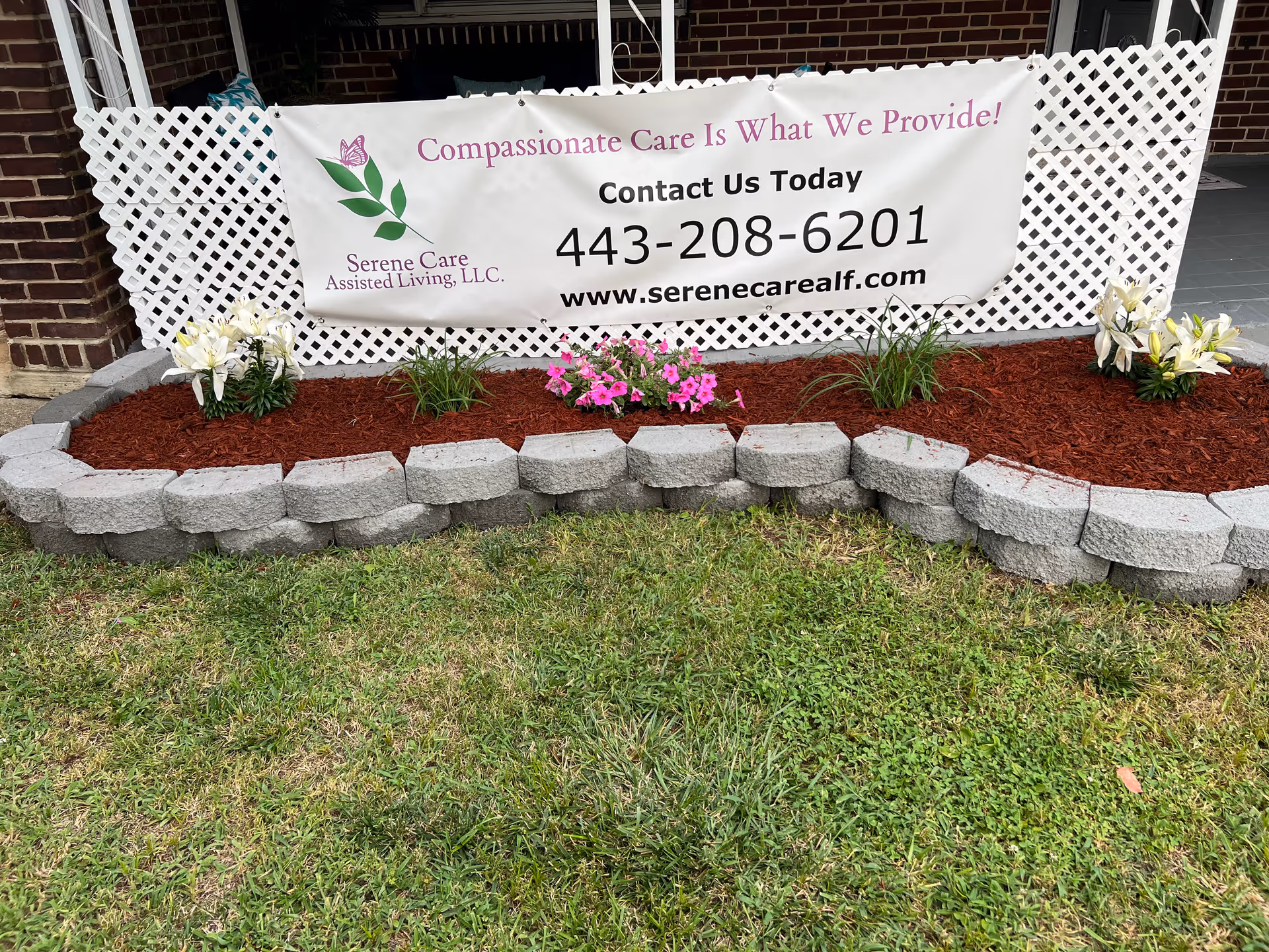 Banner advertising Serene Care Assisted Living on a front porch with flowers.