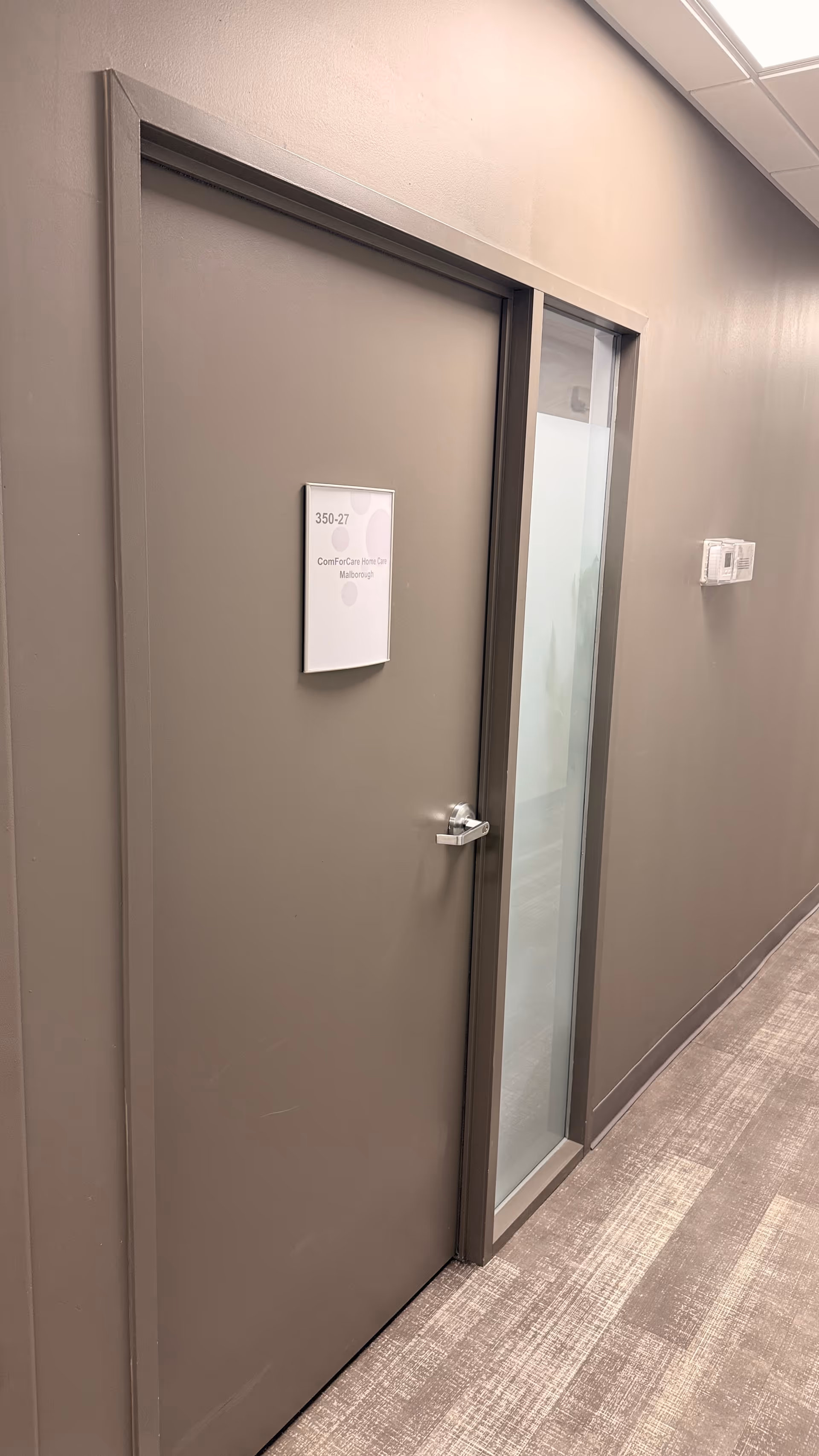 Interior hallway with a gray door labeled 350-27 beside a glass panel.