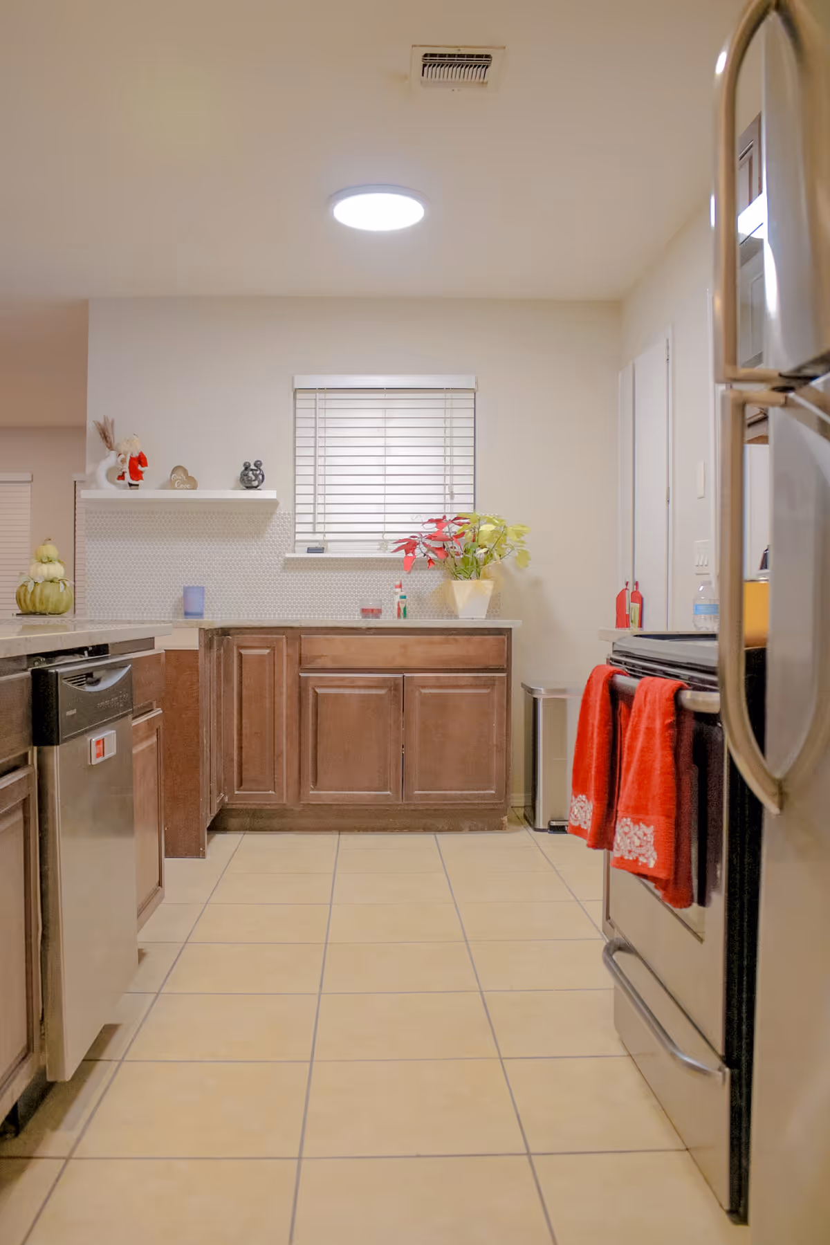 Senior living facility kitchen with wooden cabinets, stainless appliances, window, and red towels.