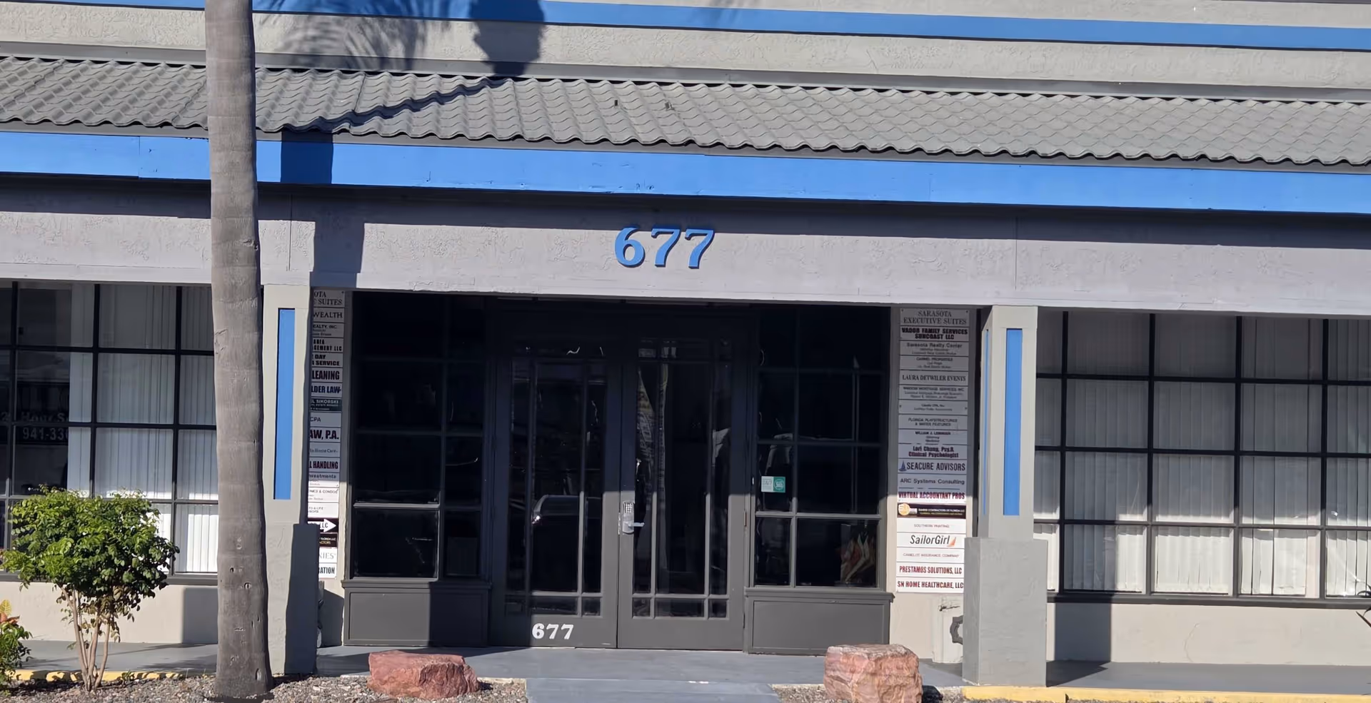 Front entrance of a commercial building with large glass doors and blue trim.