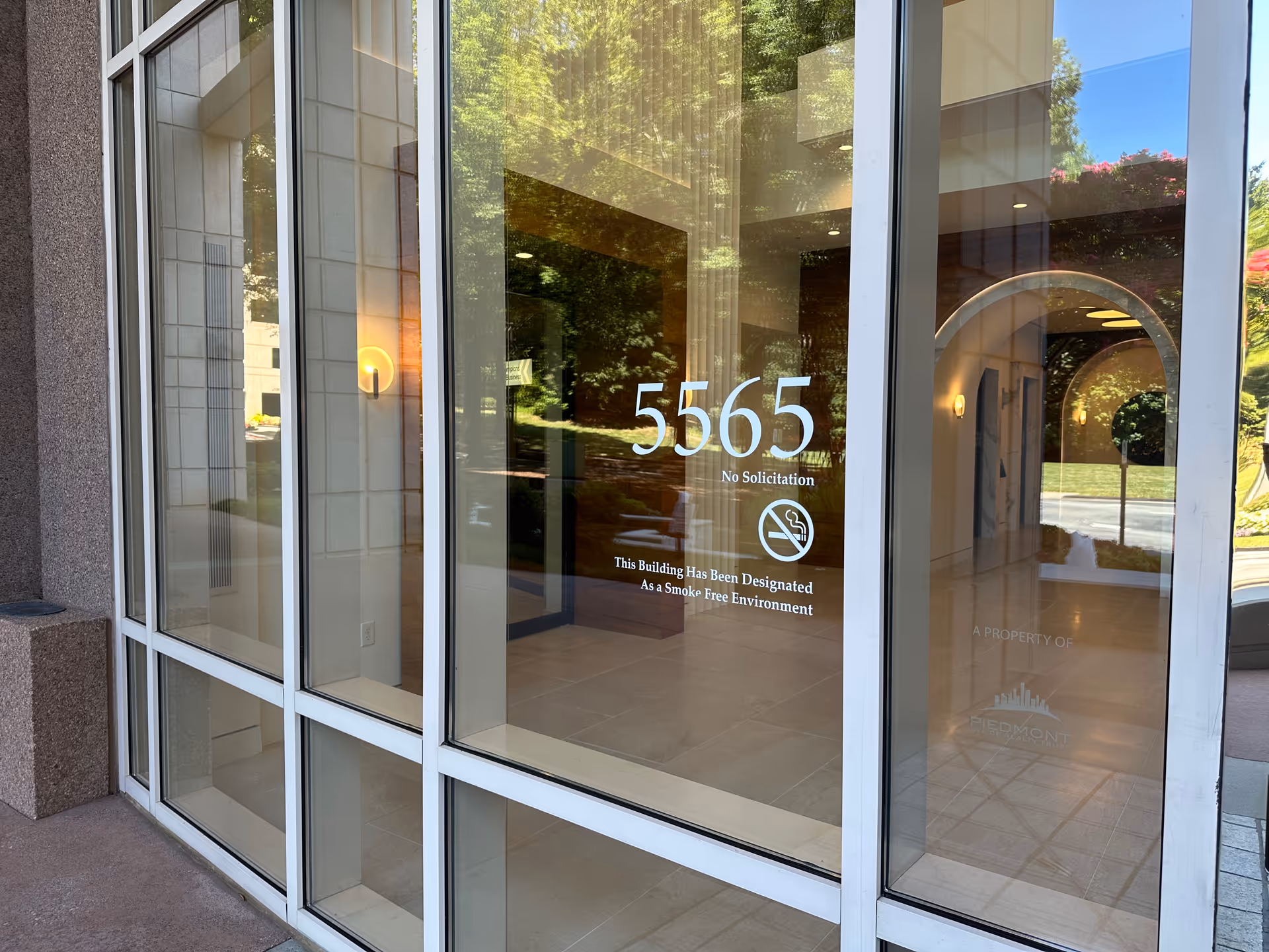 Glass entrance of a senior living facility with 5565, No Solicitation, and reflections.