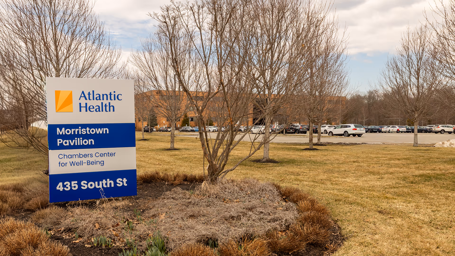 Exterior view of Atlantic Health Morristown Pavilion with a blue sign in a grassy area.
