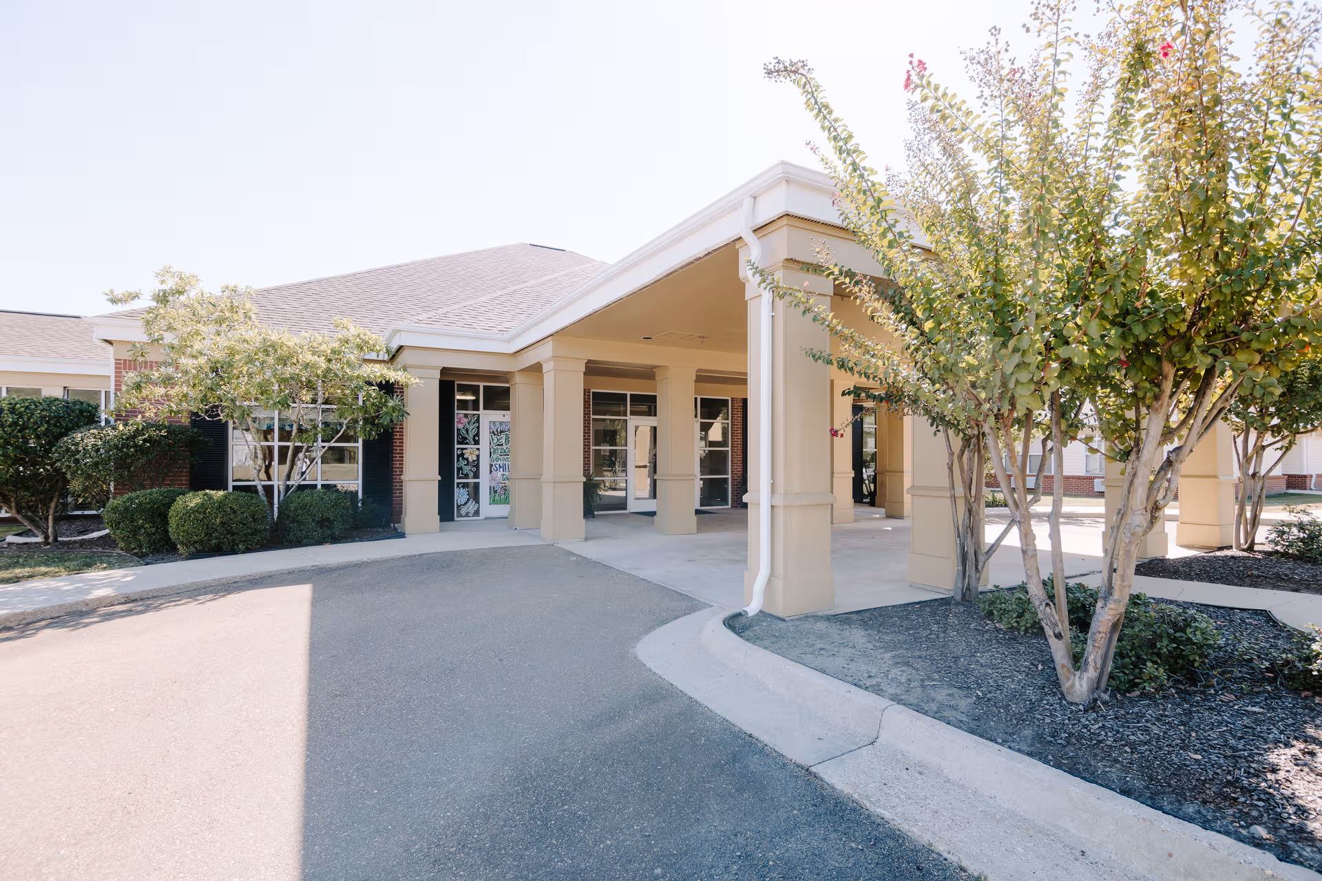 Exterior view of Courtyard Healthcare & Rehabilitation Center entrance with a covered walkway and trees.