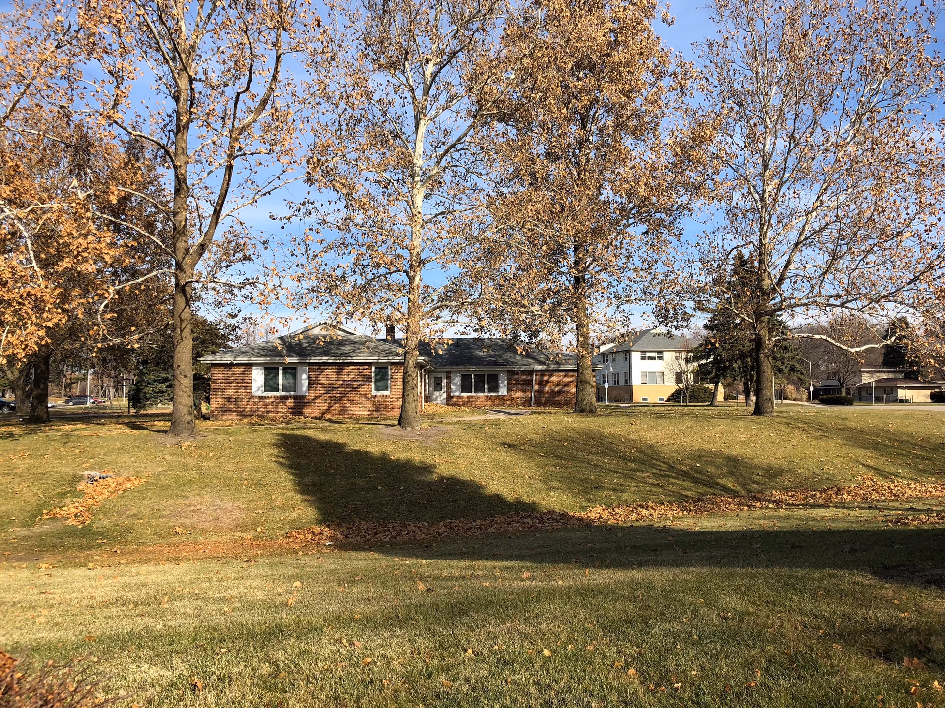Exterior view of a brick senior living facility with trees and a grassy lawn