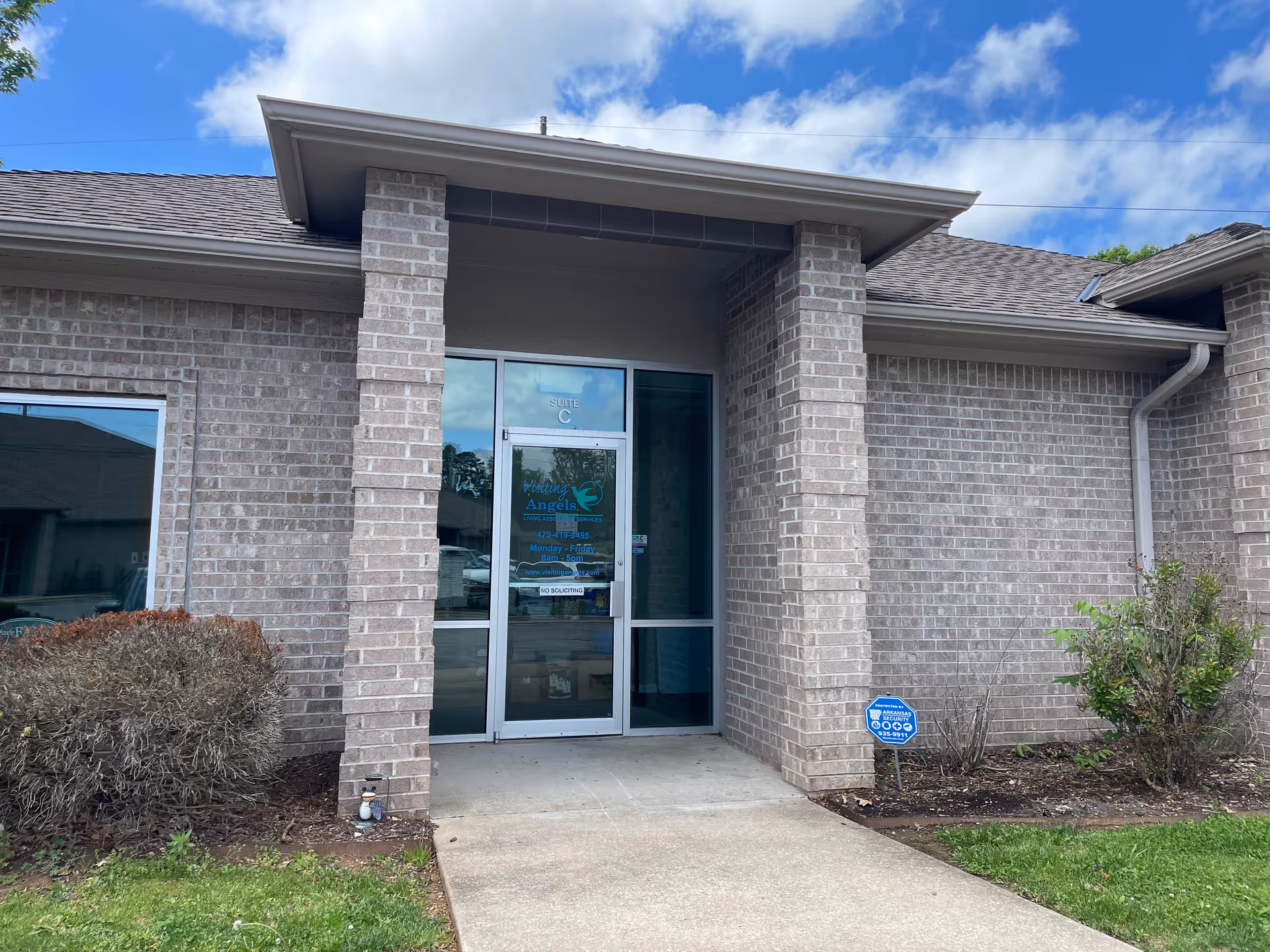 Brick building entrance with glass door and blue sky overhead.