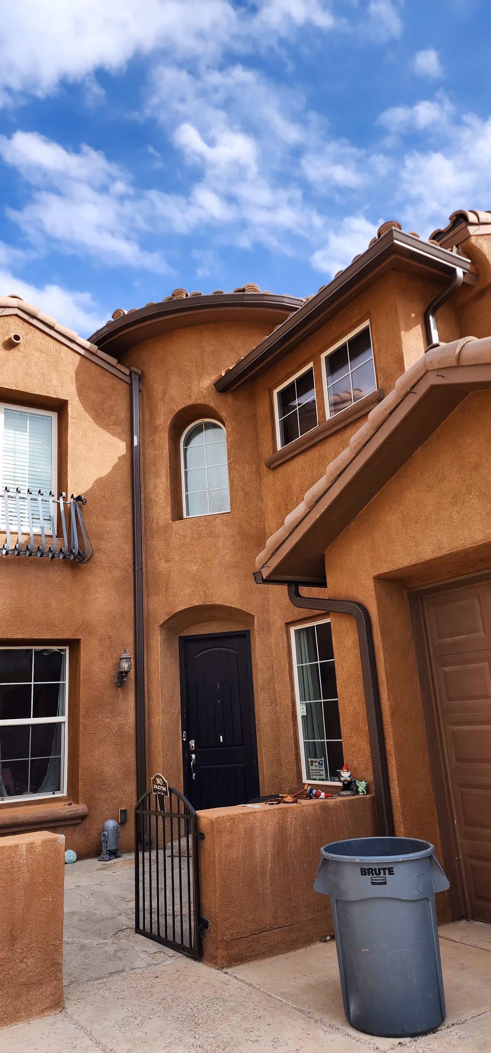 Orange stucco senior living building exterior with arched doorway and gate.