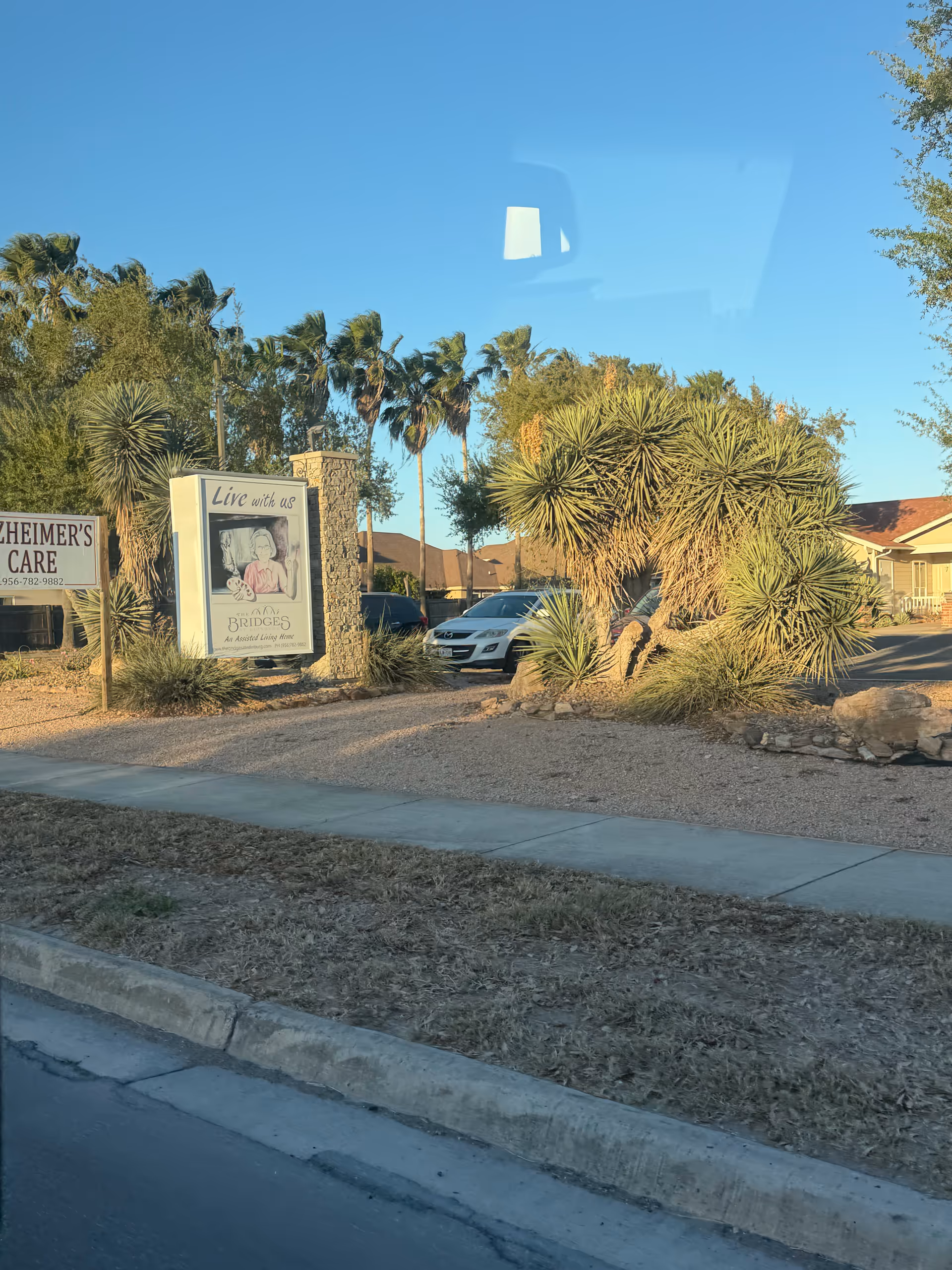 Exterior view of Edinburg Nursing and Rehabilitation Center with palm trees and signs.