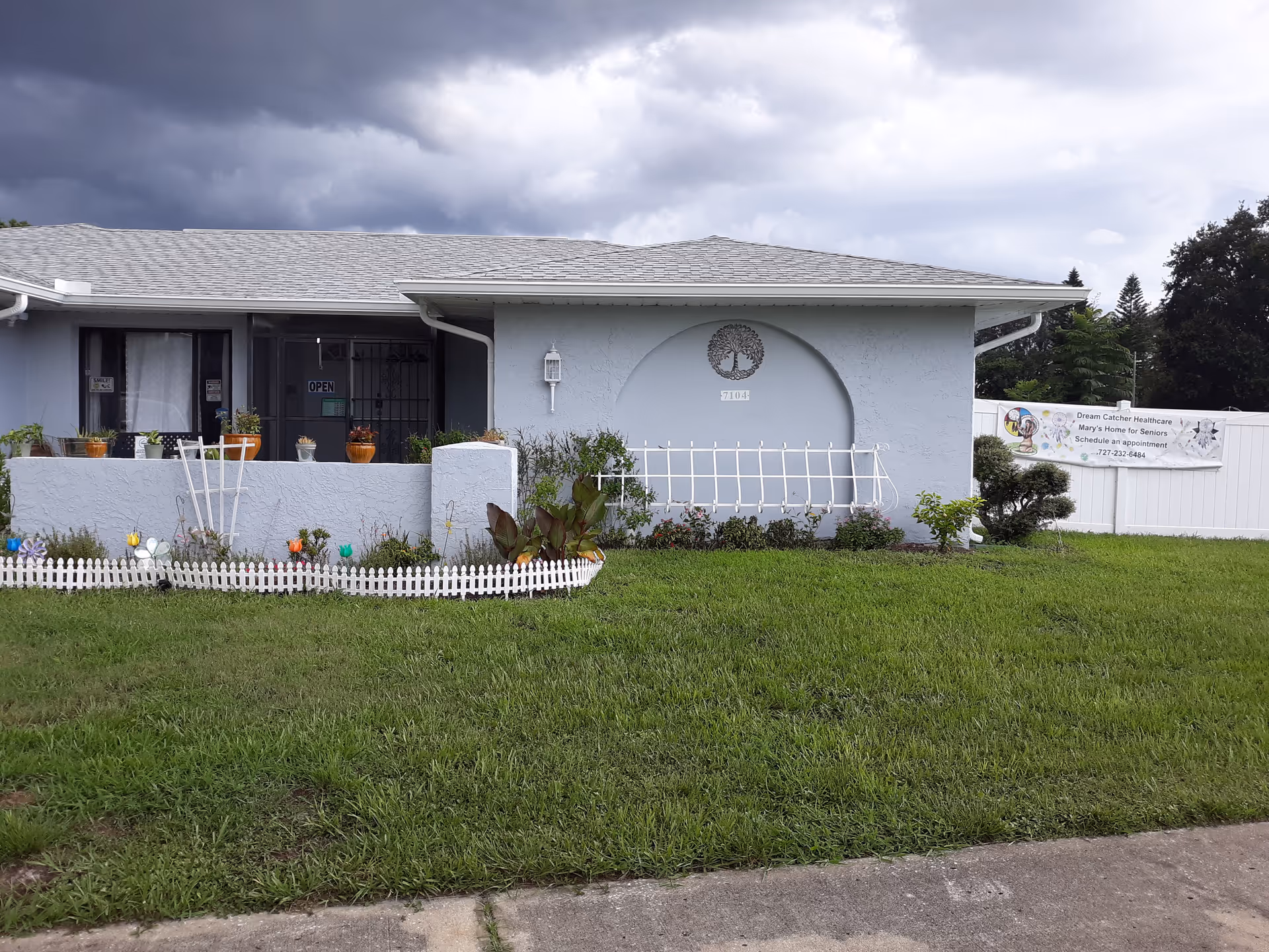 Front of a light-blue, single-story facility with a small garden and a Dream Catcher banner.