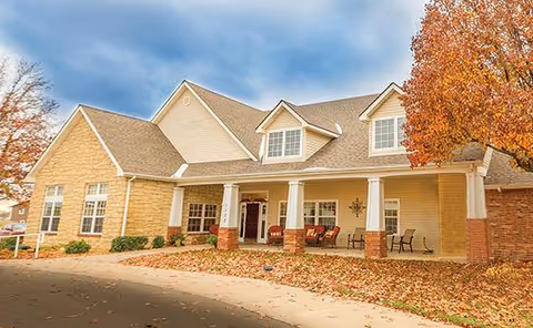 Exterior view of Russet Adult Family Home with a welcoming porch, seating, and autumn foliage.