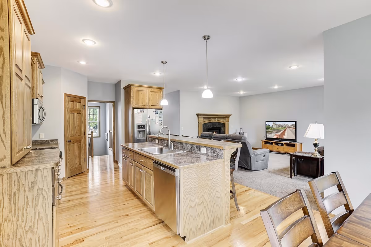 Open-concept kitchen and living area with island, seating, and a fireplace.