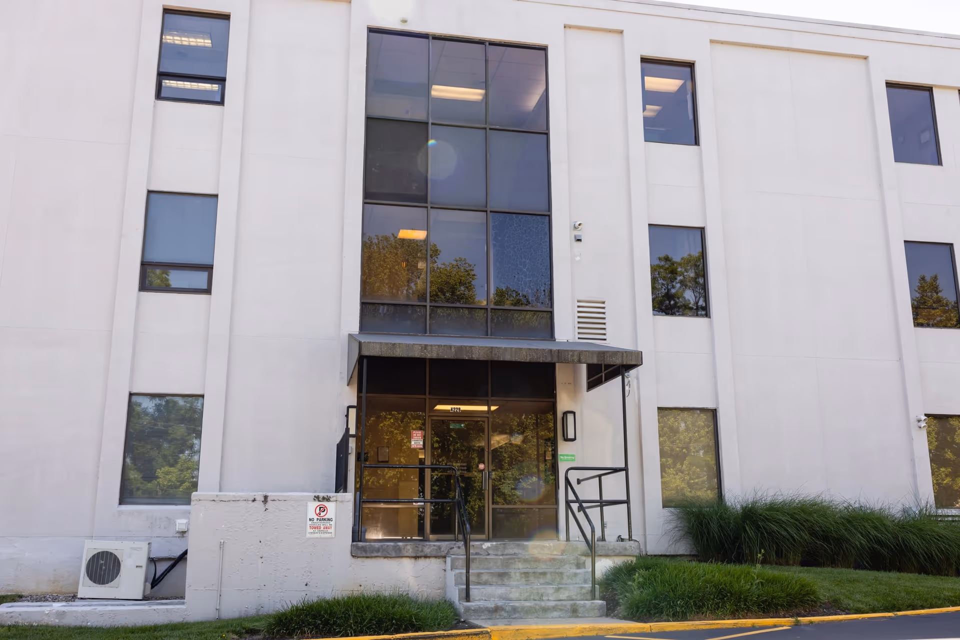 Front view of a white multi-story building with a glass entrance for Joycare For Elders Homecare