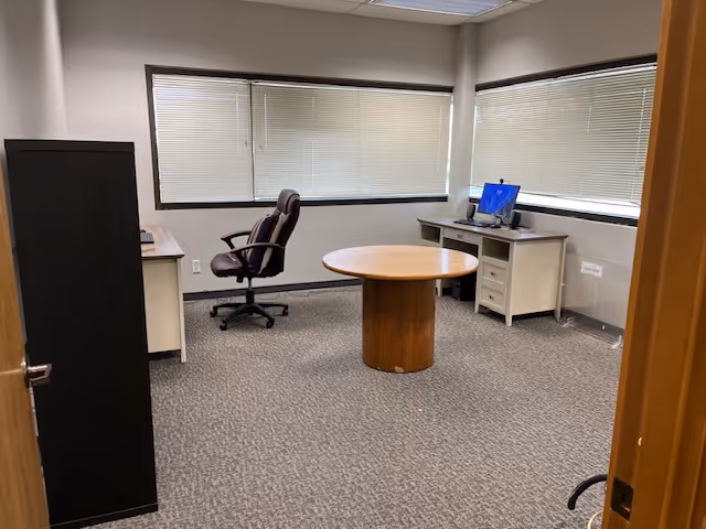 Office space in a senior living facility with round table and computer desk.