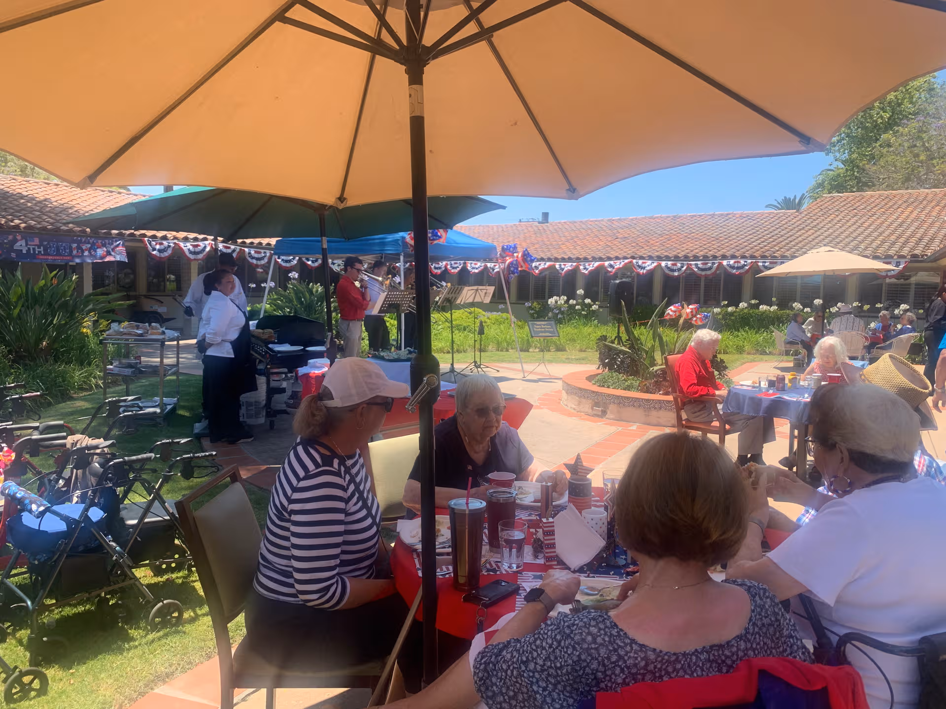 Outdoor courtyard with residents dining at tables under umbrellas